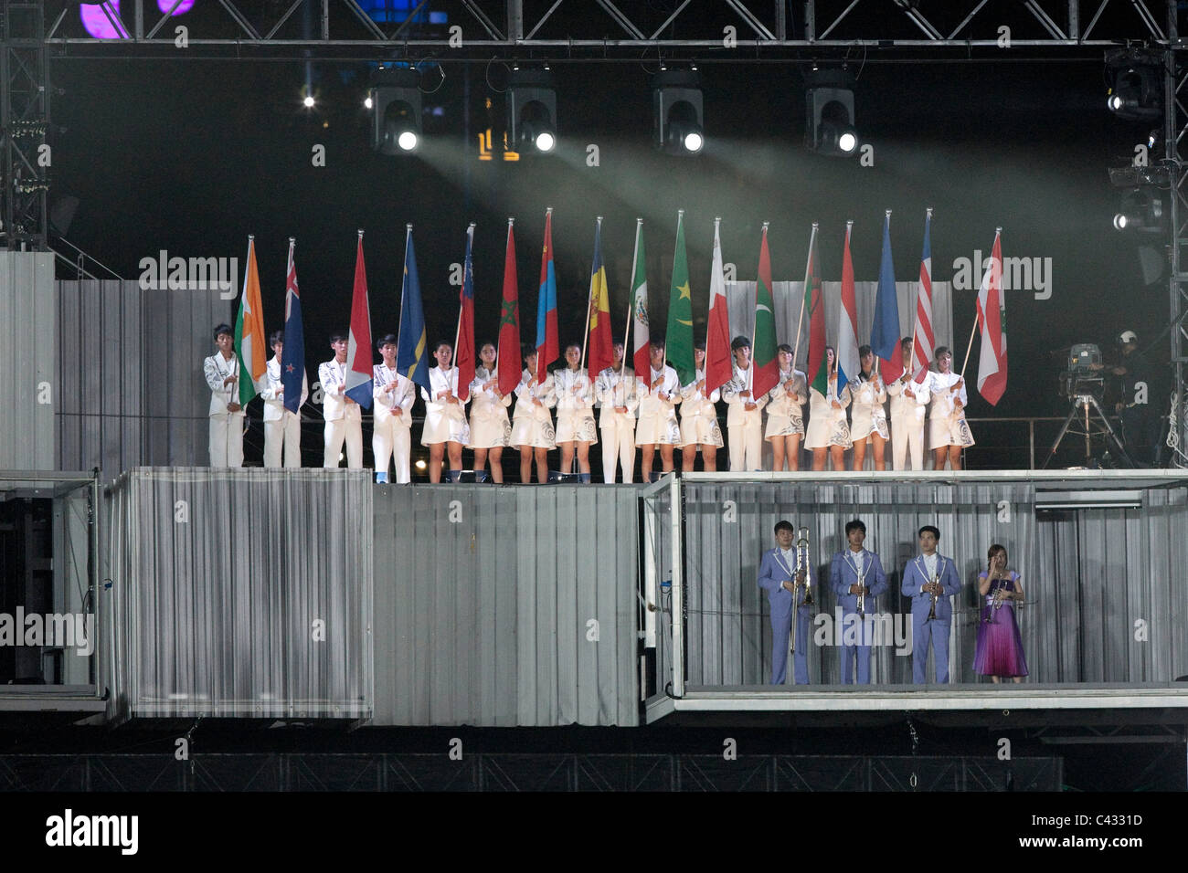 Gli artisti interpreti o esecutori che sorreggono le bandiere delle nazioni mentre la bandiera olimpica è sollevata durante il 2010 Olimpiadi della Gioventù cerimonia di apertura. Foto Stock