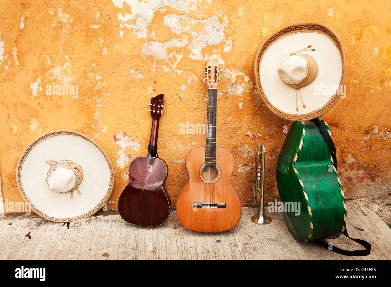 Gli strumenti musicali messicani e i sombreros riposano contro un muro di squalo con la vernice da peeling Foto Stock