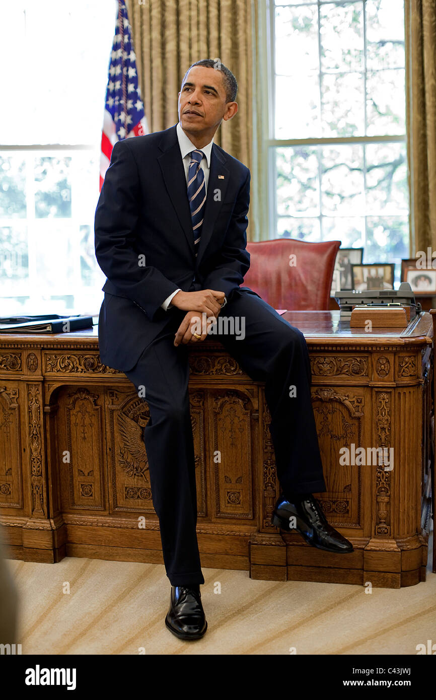 Il presidente Barack Obama si appoggia contro la risoluta scrivania in ufficio ovale Foto Stock