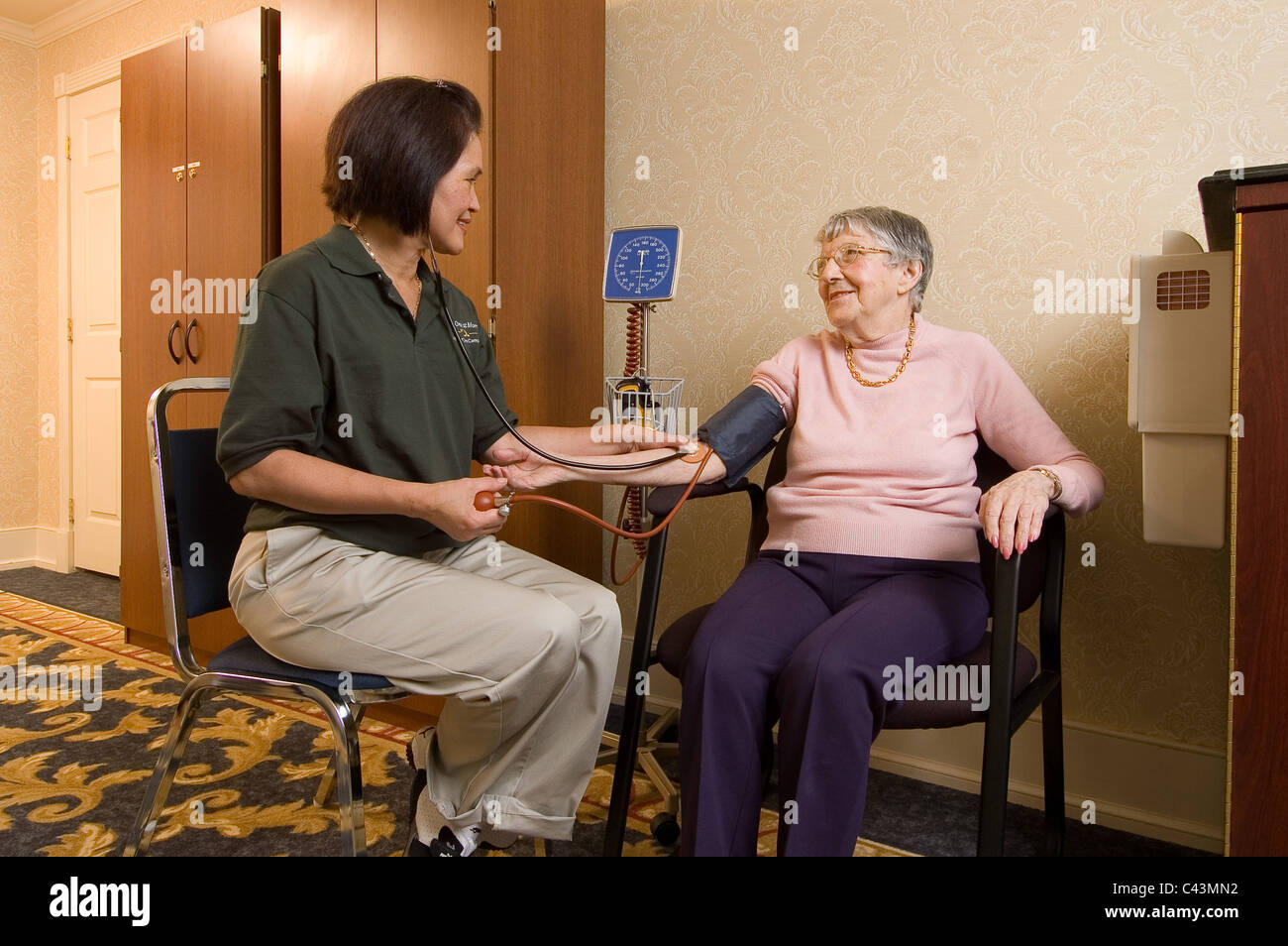 Un infermiere in un assisted living facility controlla la pressione del sangue di un residente Foto Stock