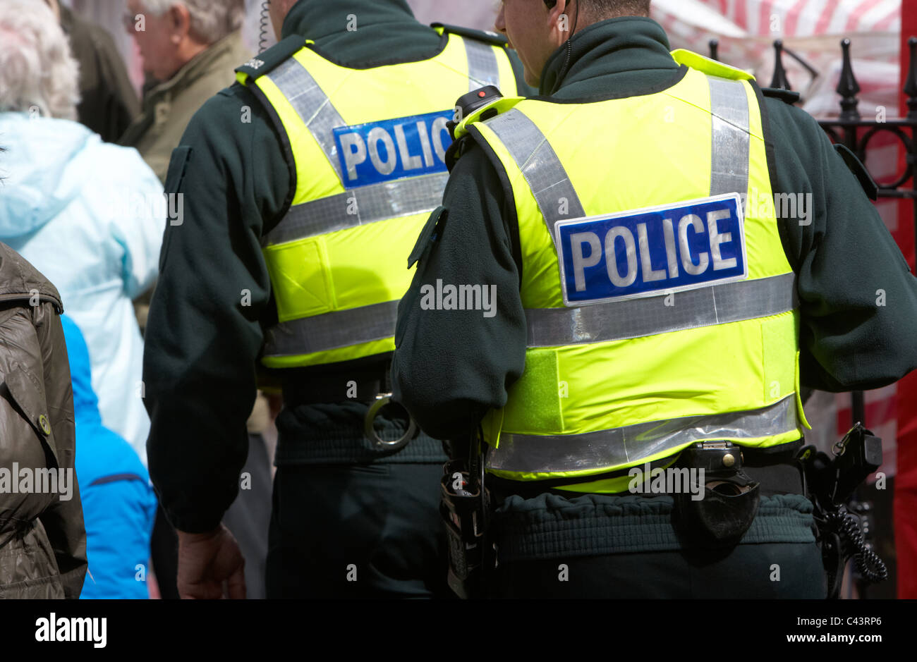 Poliziotti armati indossando stab prova giubbotti antiproiettile a piedi attraverso la folla Foto Stock