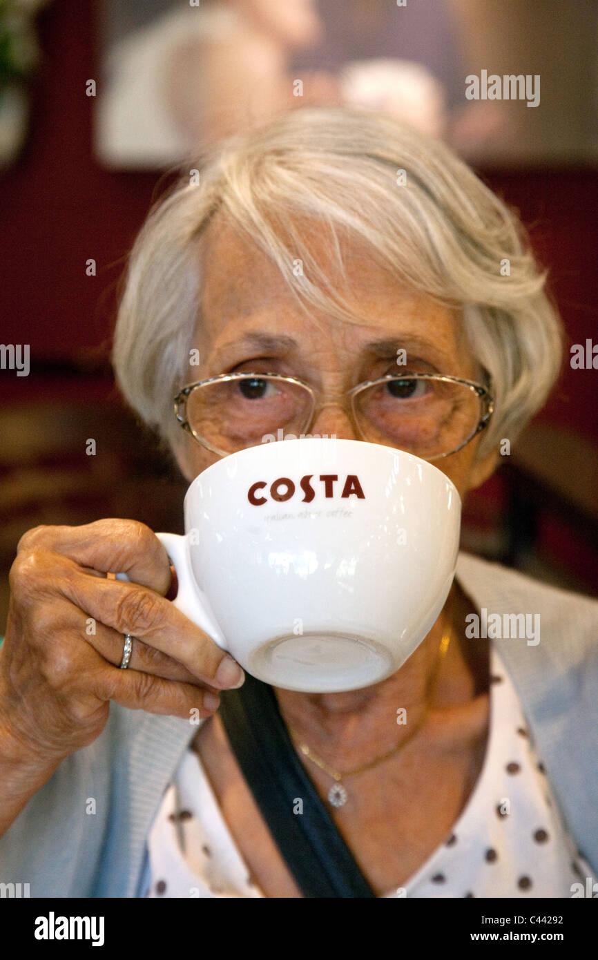 Una signora anziana gustando una tazza di caffè, caffè Costa, Exeter servizi autostradali, M5 Devon UK Foto Stock