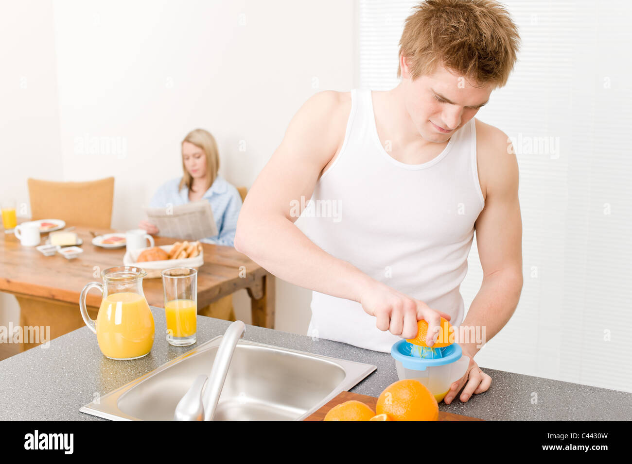 La colazione felice coppia fare il succo di arancia in cucina di mattina Foto Stock