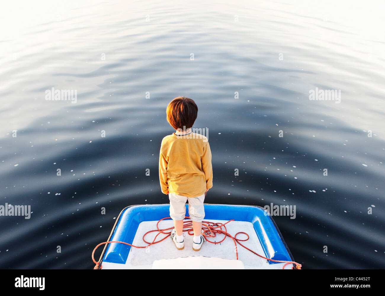 Un ragazzo in piedi sul bordo di un pontile galleggiante Foto Stock
