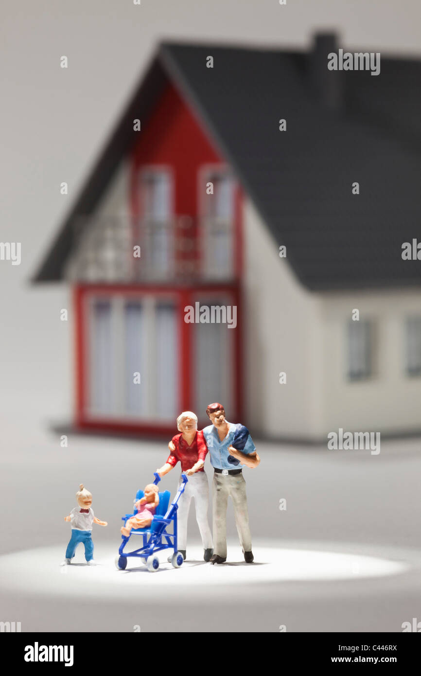 Una giovane famiglia di statuette in miniatura nella parte anteriore di una casa Foto Stock