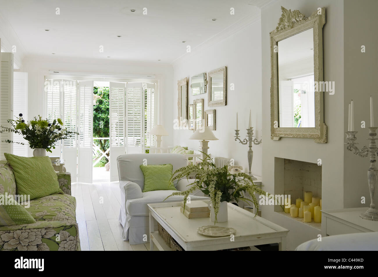 White stanza vivente con il camino, specchio, composizioni floreali e poltrone Foto Stock