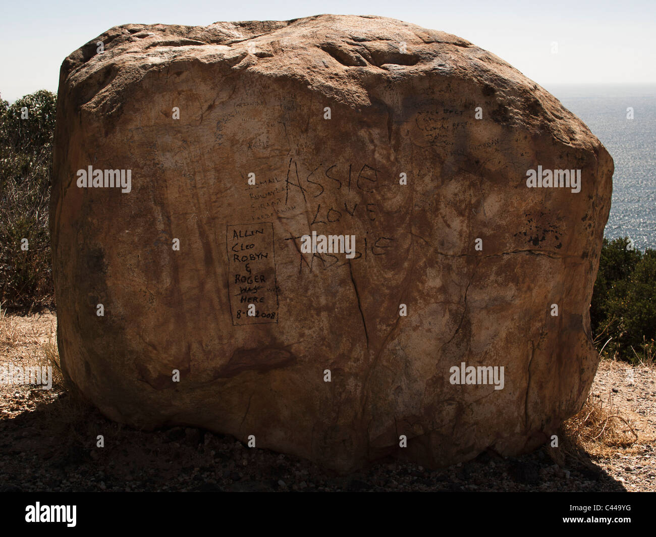 Grande masso con messaggi scritti su di esso e il mare in background Foto Stock