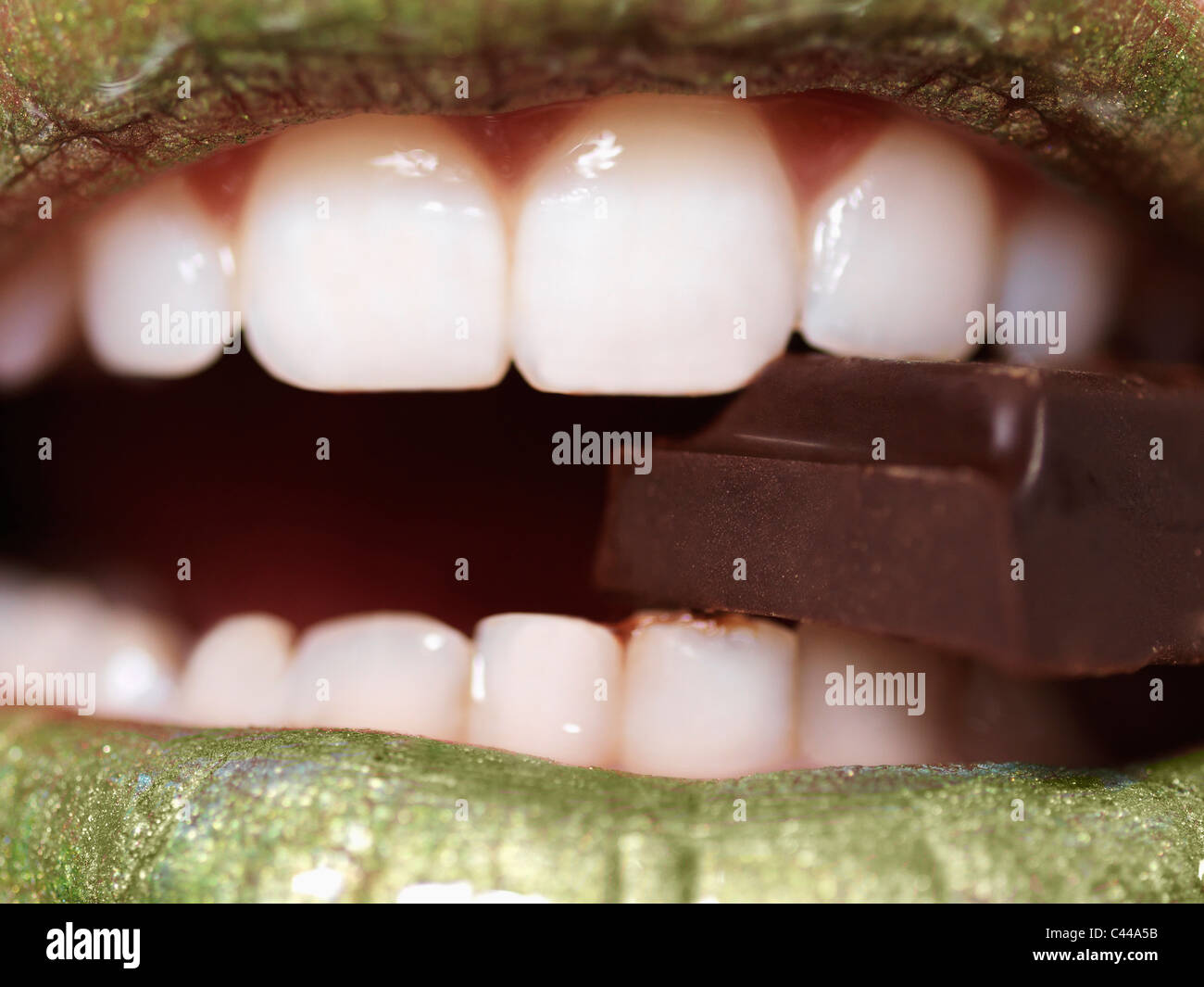 Una donna di mangiare un pezzo di cioccolato, extreme close up di bocca Foto Stock