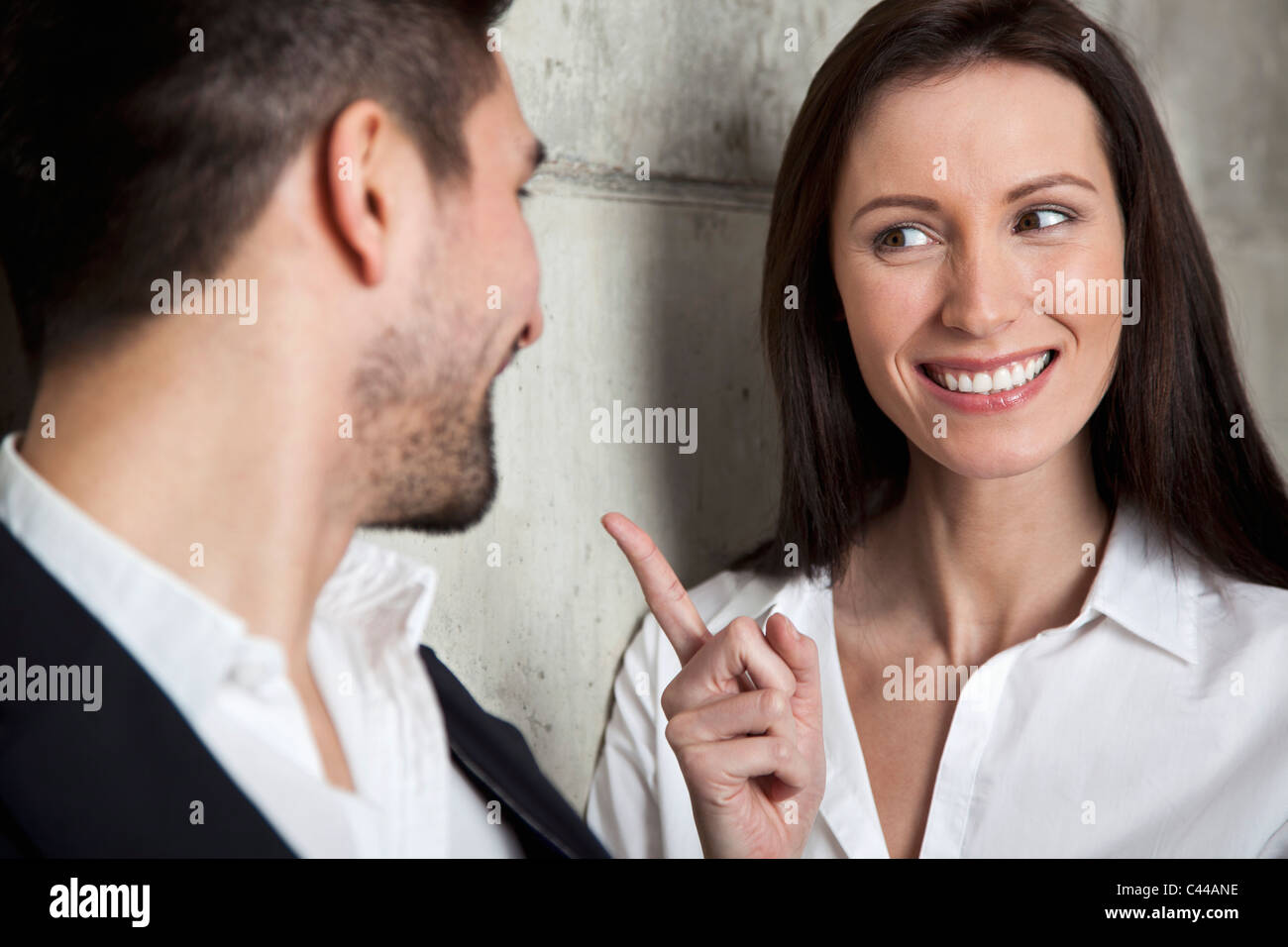 Un sorridente imprenditrice scolding un imprenditore Foto Stock