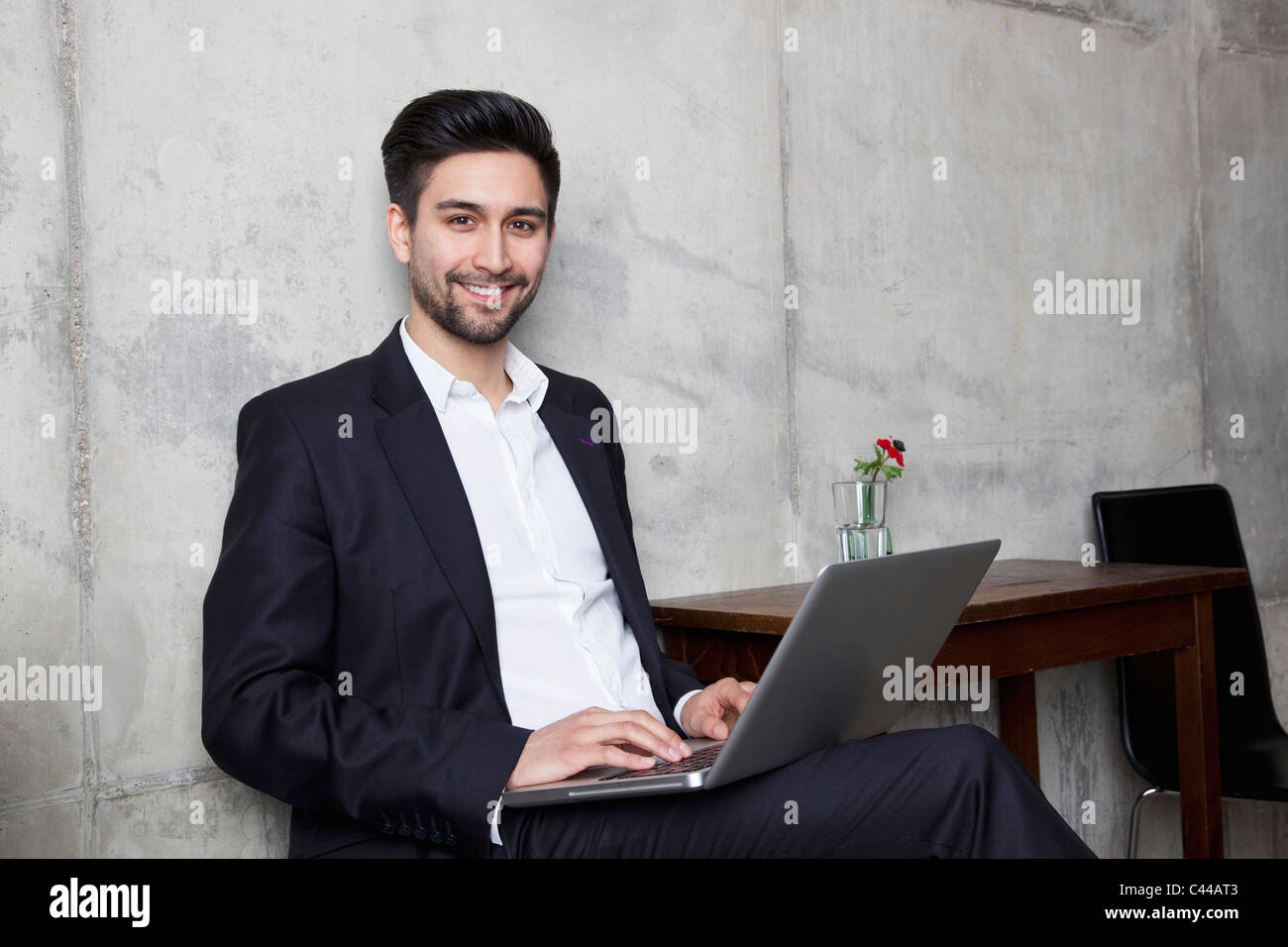 Un imprenditore sorridente al lavoro su un notebook Foto Stock