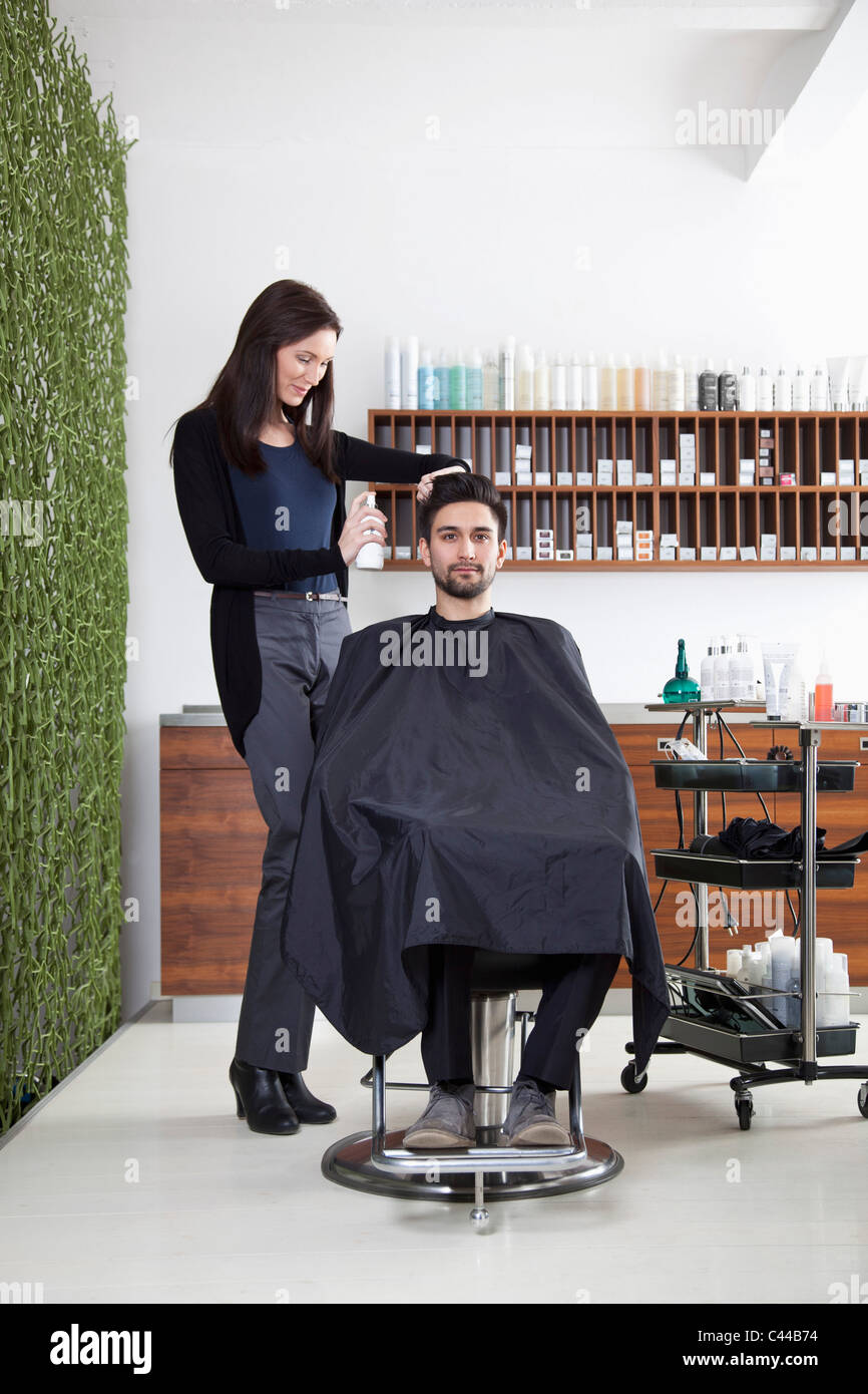 Un parrucchiere la spruzzatura di prodotto a un cliente i capelli Foto Stock