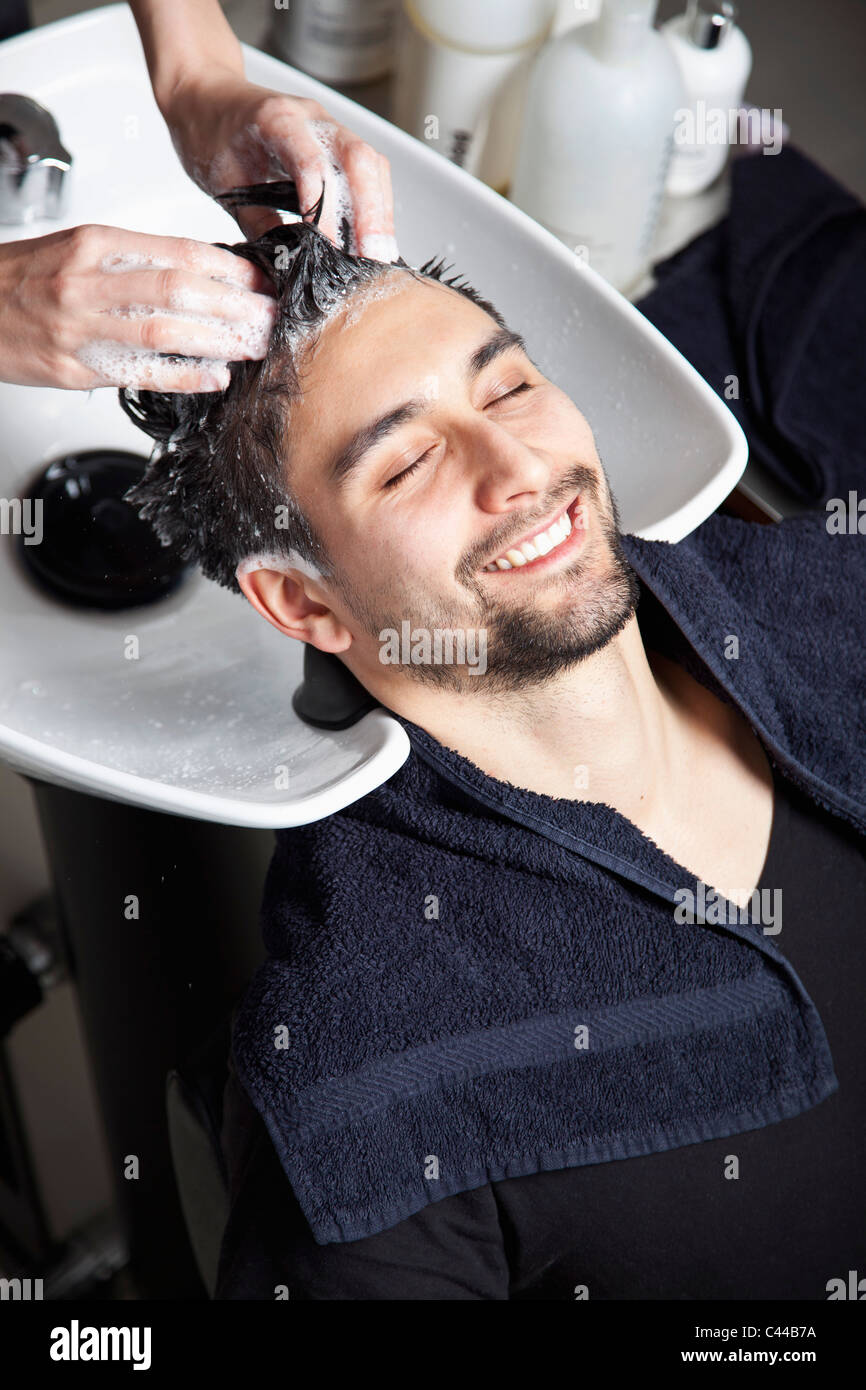 Un uomo avente i suoi capelli lavati a un parrucchiere Foto Stock