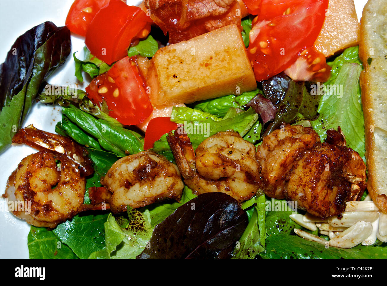 Pasto insalata di dimensione pan gamberi fritti cubettato di pomodoro il prosciutto tagliato a cubetti canatalope verdure miste slivered mandorle aglio lato toast Foto Stock