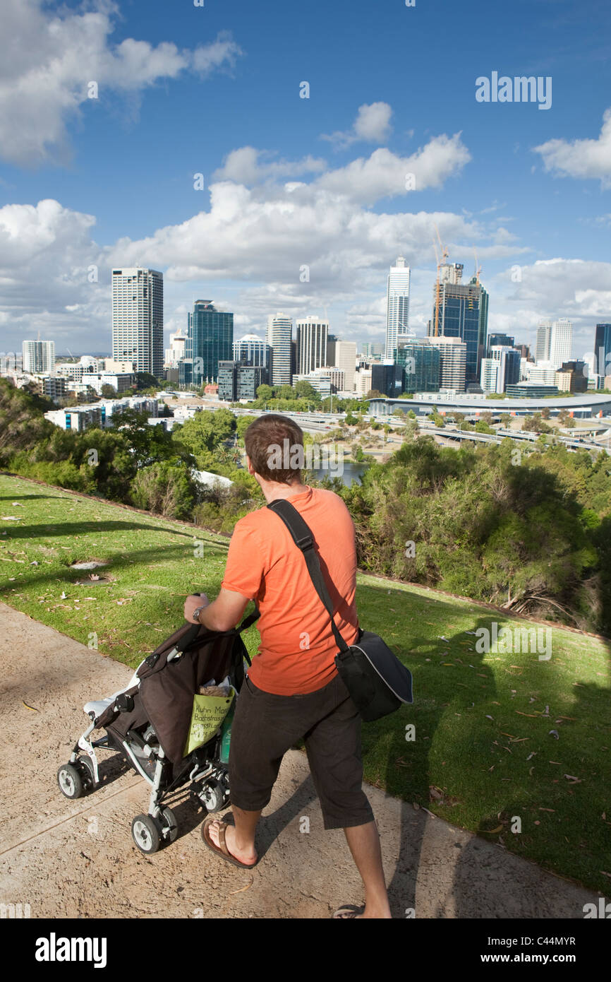 Uomo di spingere un passeggino con vista dello skyline della città da Kings Park. Perth, Western Australia, Australia Foto Stock