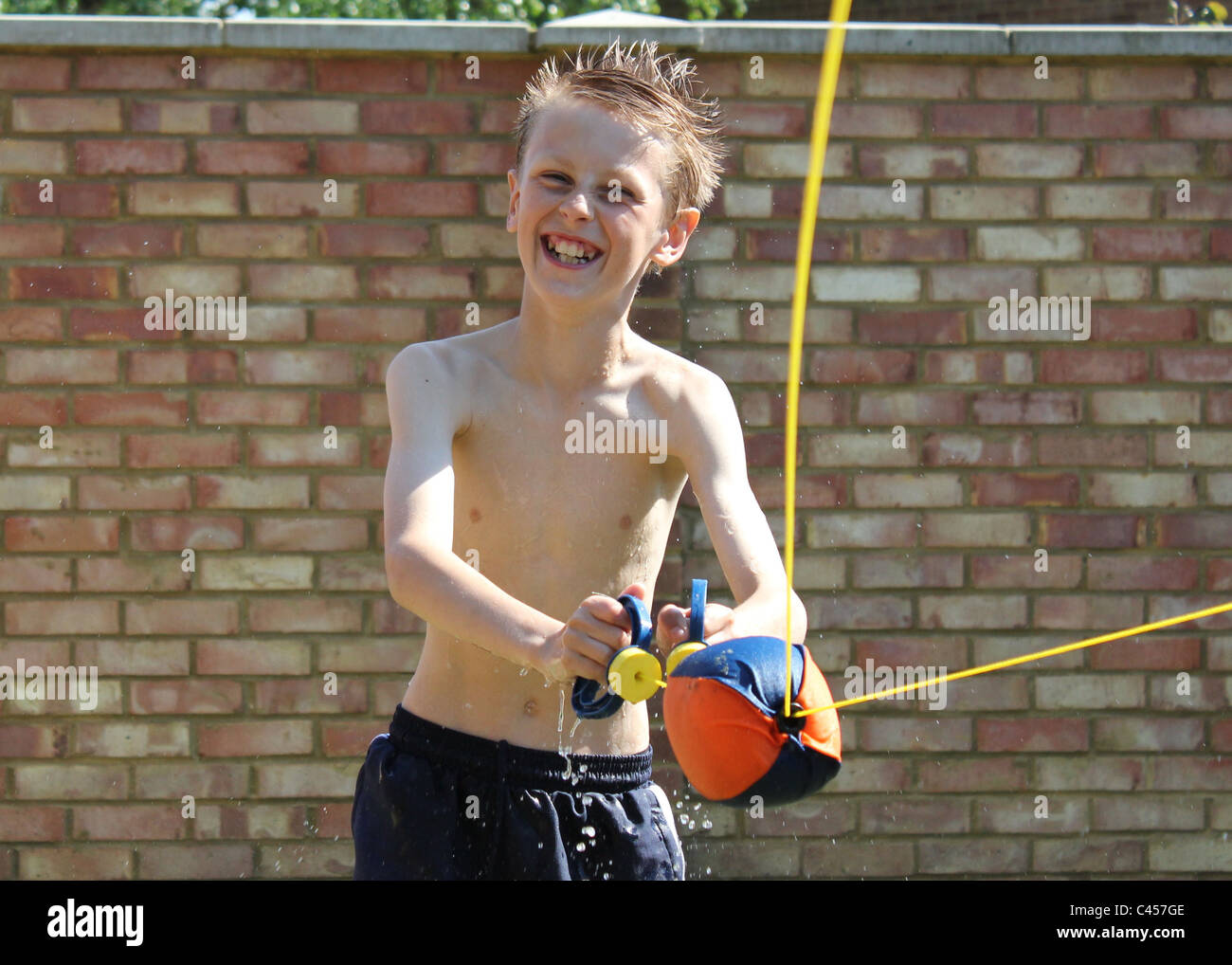 Ragazzo giocando gioco d'acqua sotto il sole Foto Stock