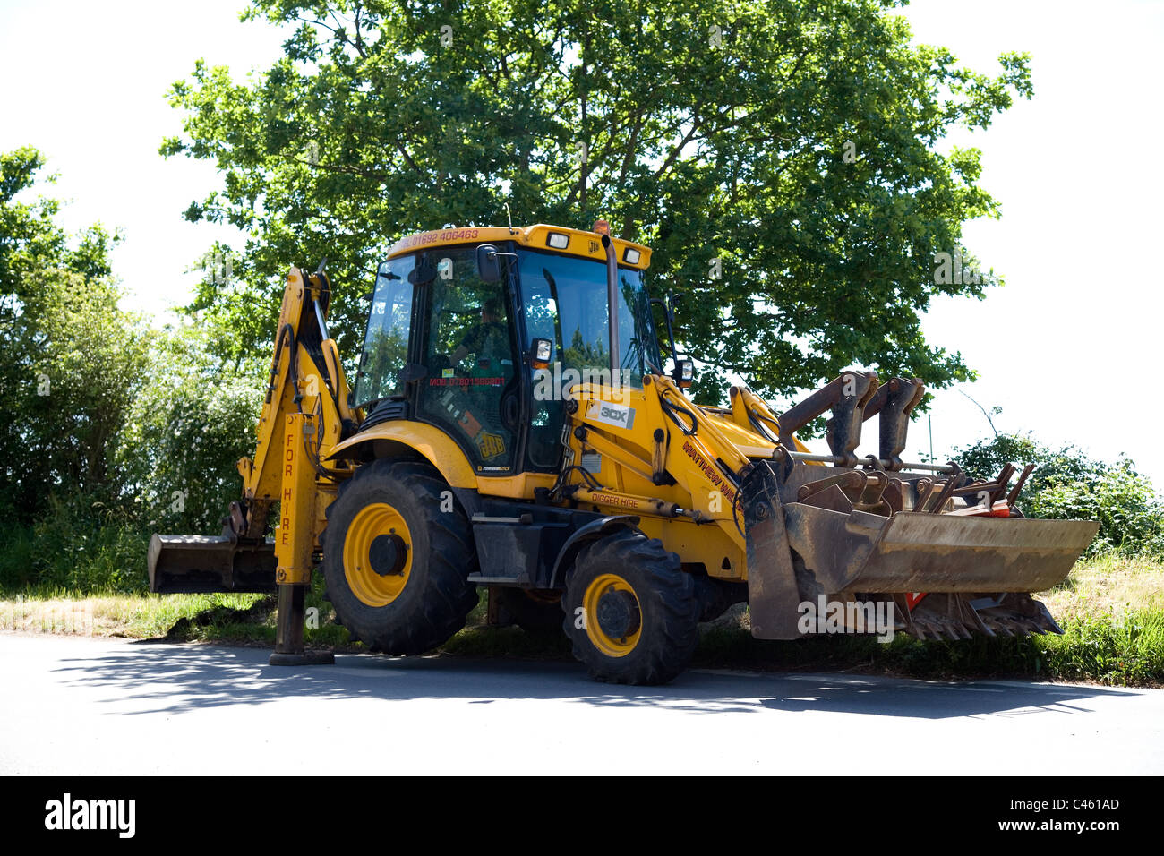 JCB 3CX caricatore retroescavatore escavatore, visto qui nelle zone rurali a Norfolk clearing fossati per il dipartimento autostrade in una giornata di sole. Foto Stock