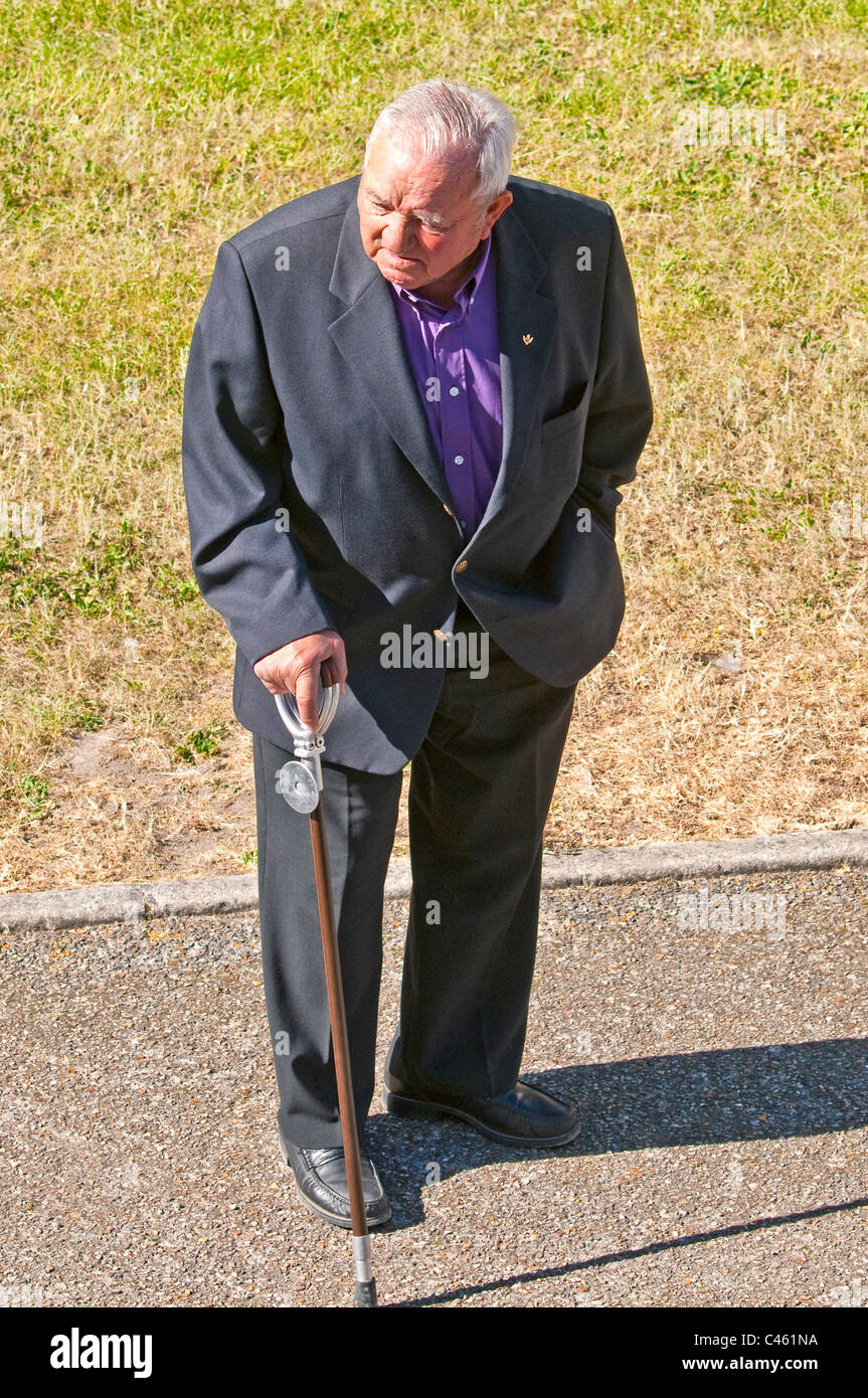 Uomo vecchio con bastone di ripresa in attesa sul marciapiede - Francia. Foto Stock