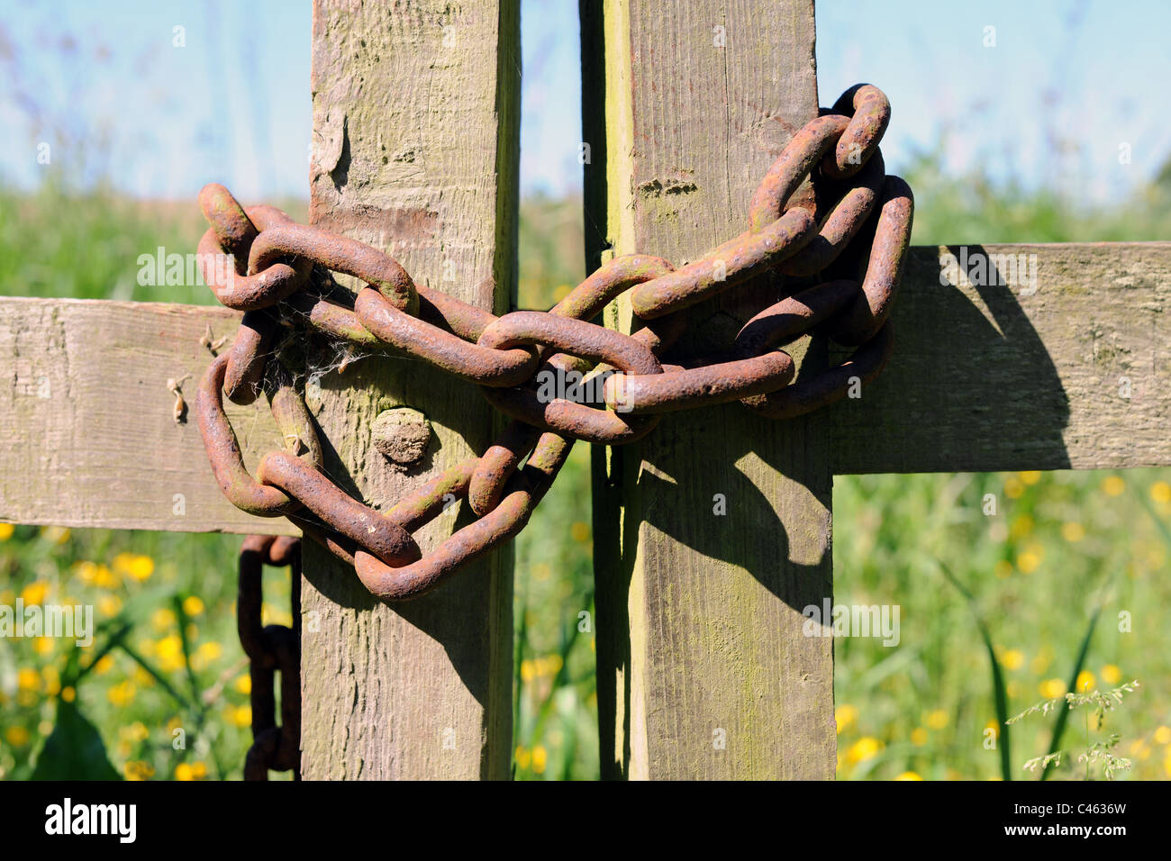 Un paesaggio cancello in legno incatenato per impedire l'accesso a un prato o campo Foto Stock