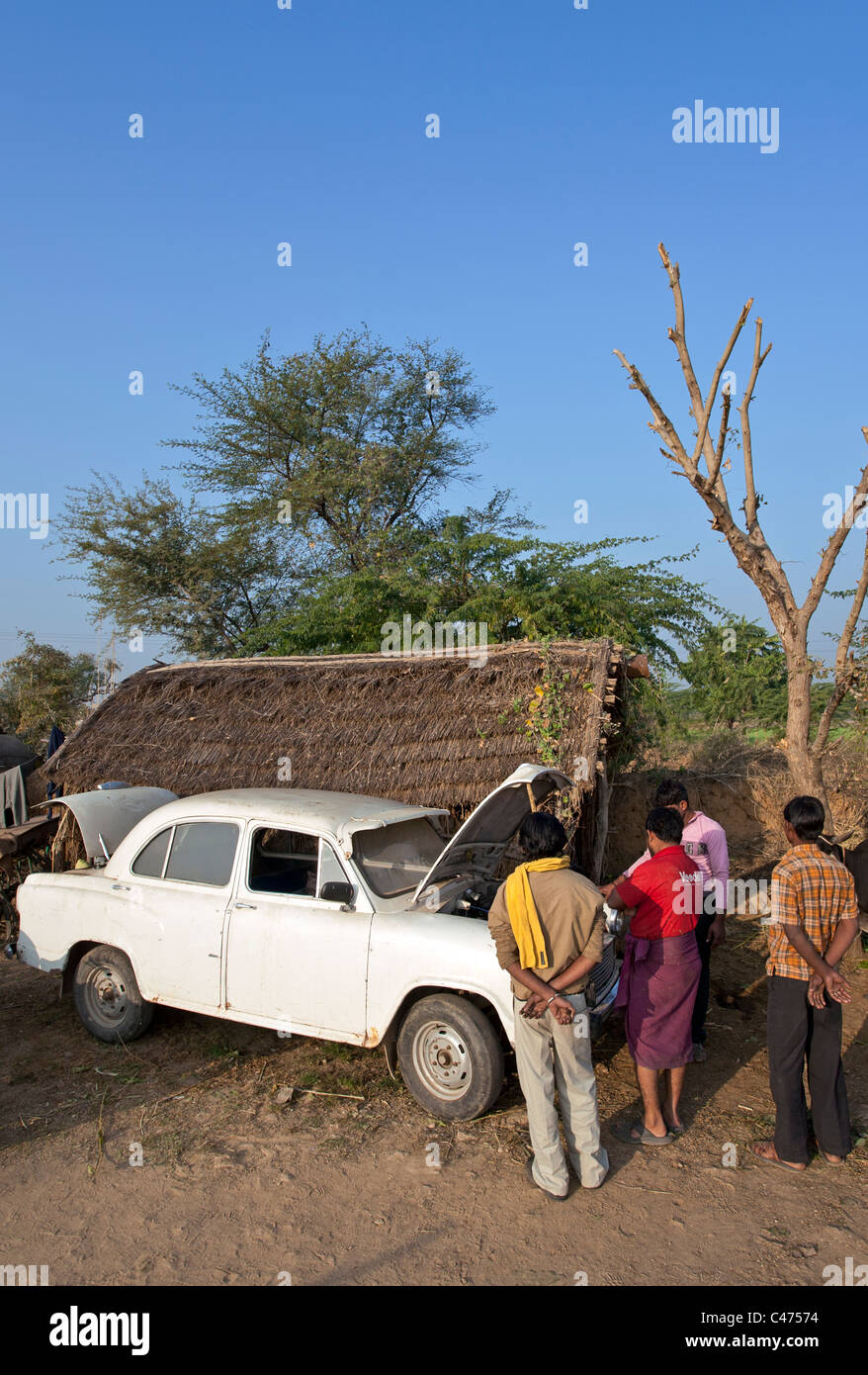 Indian uomini riparare un vecchio hindustan ambasciatore auto. Pushkar. Il Rajasthan. India Foto Stock