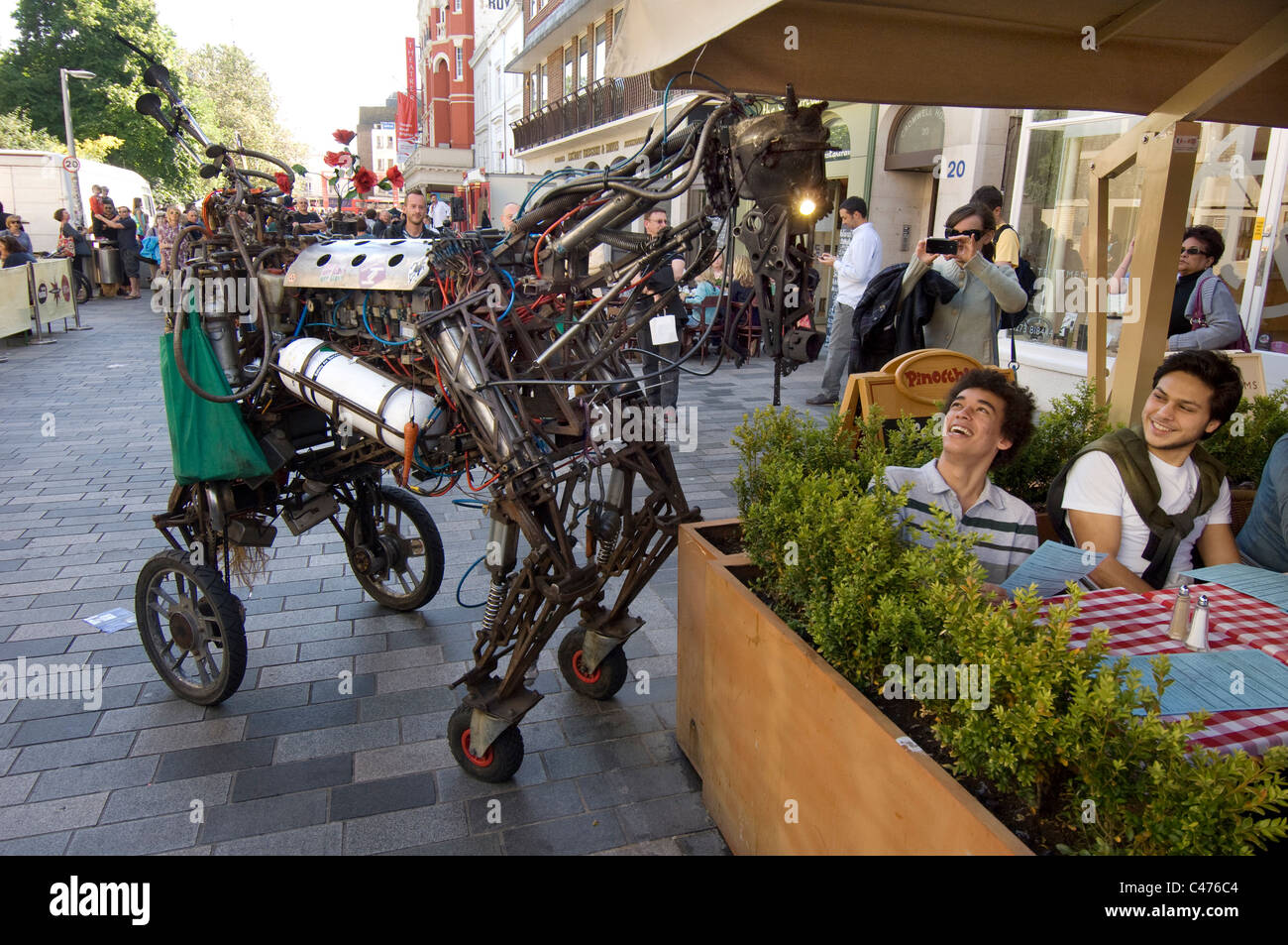 Un cavallo meccanico amuses due maschi giovani turisti come parte del teatro di strada per il 2011 Brighton Festival Fringe Foto Stock