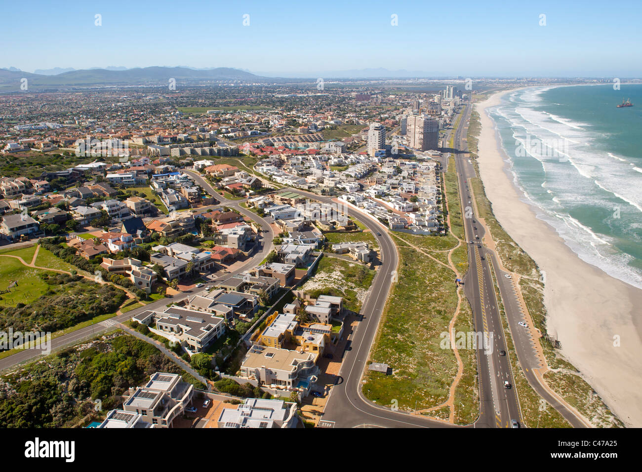 Vista aerea giù in spiaggia e oltre la periferia di West Beach, Blouberg e vista tabella in Cape Town, Sud Africa. Foto Stock