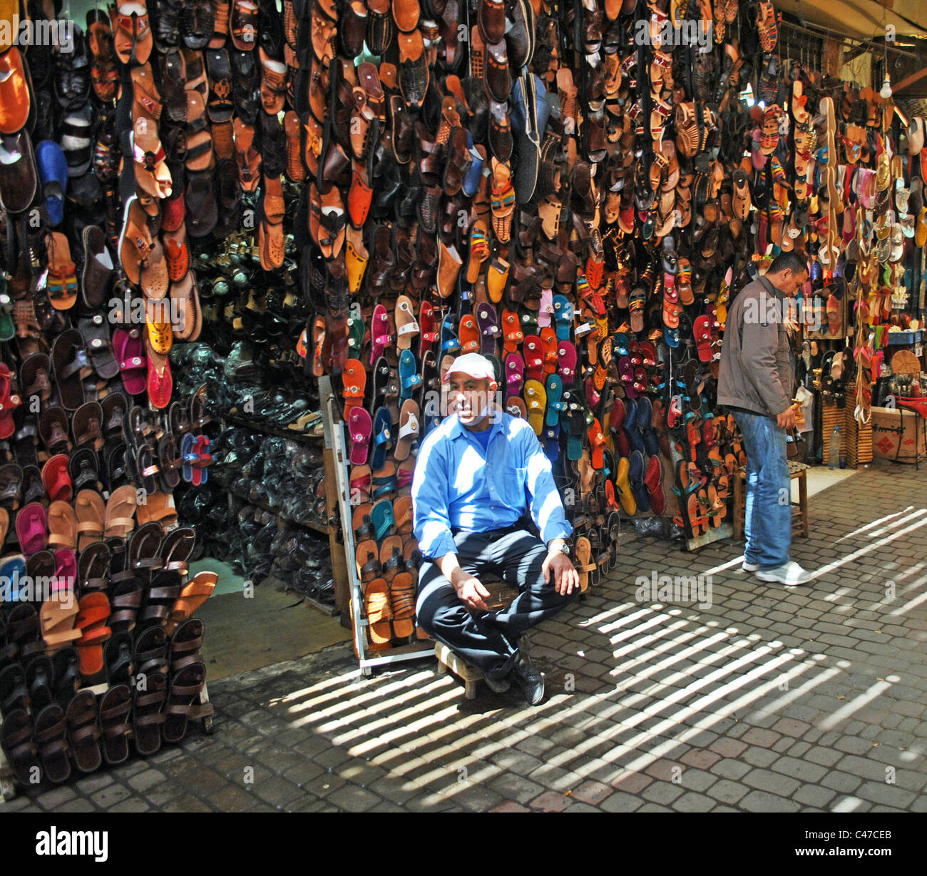 L'uomo la vendita di scarpe in un souk di Marrakech, Marocco Foto Stock