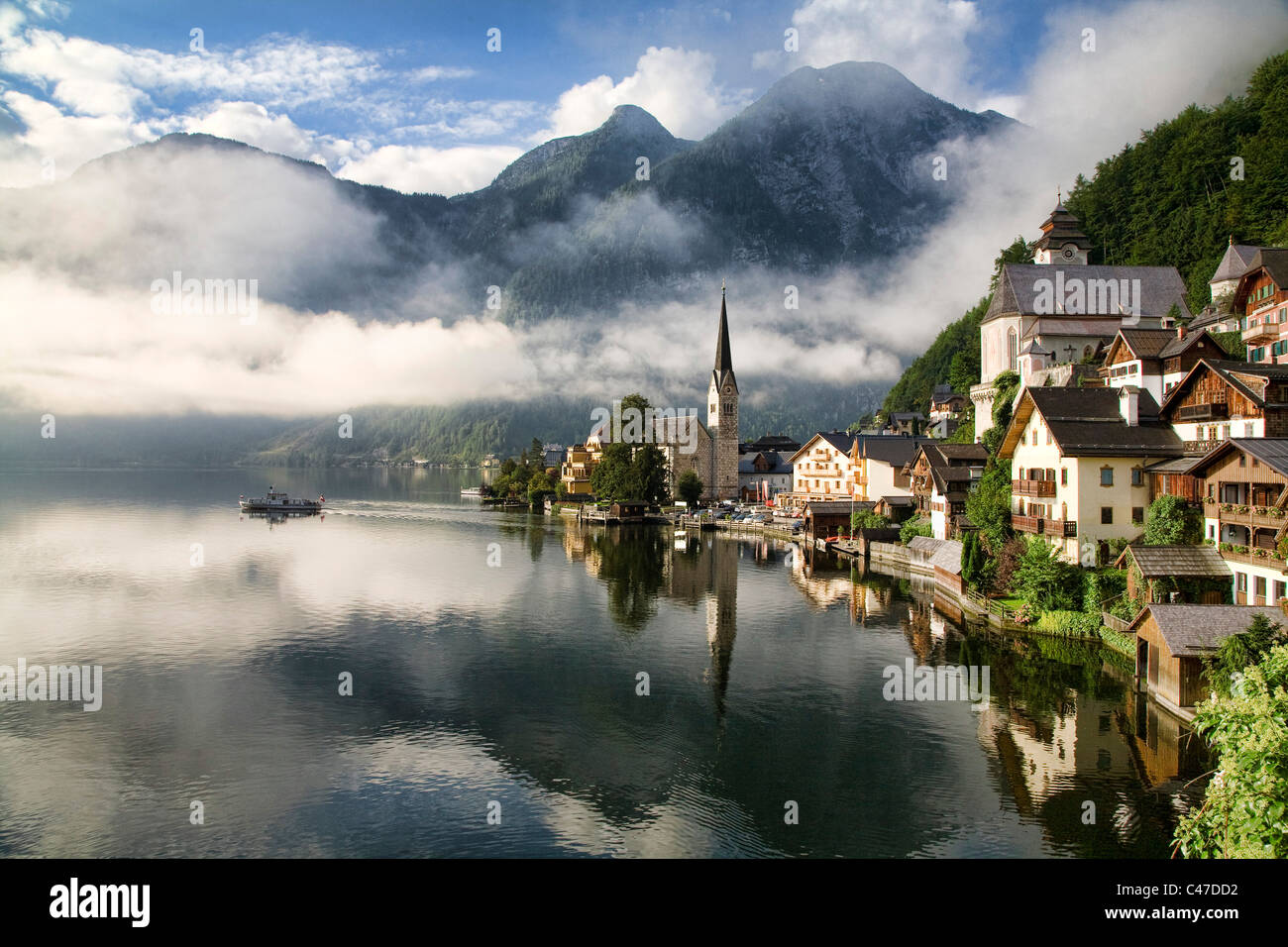 Il sole del mattino si riattiva Hallstatt, Austria come un acqua taxi inizia attraverso il Hallstatter vedere. Foto Stock