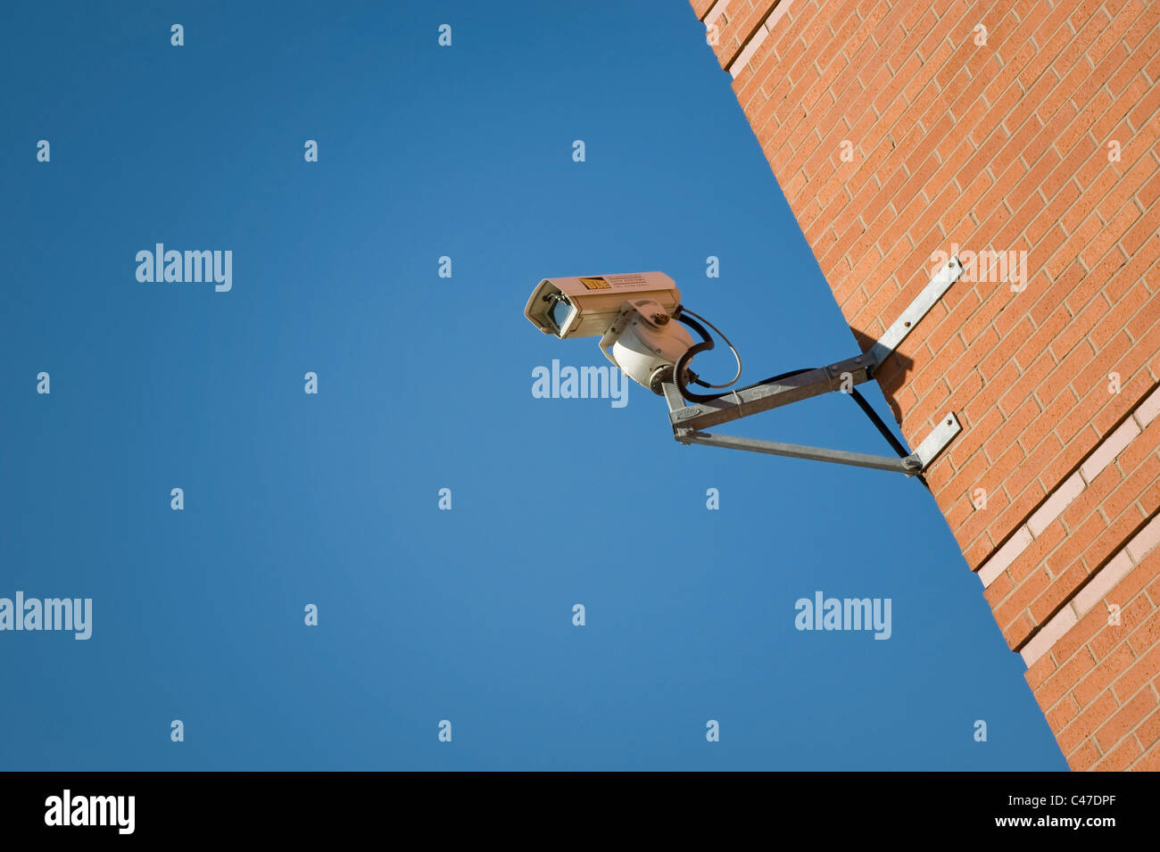 Una telecamera TVCC attaccato ad un muro di mattoni su un luminoso e cielo chiaro giorno. Foto Stock