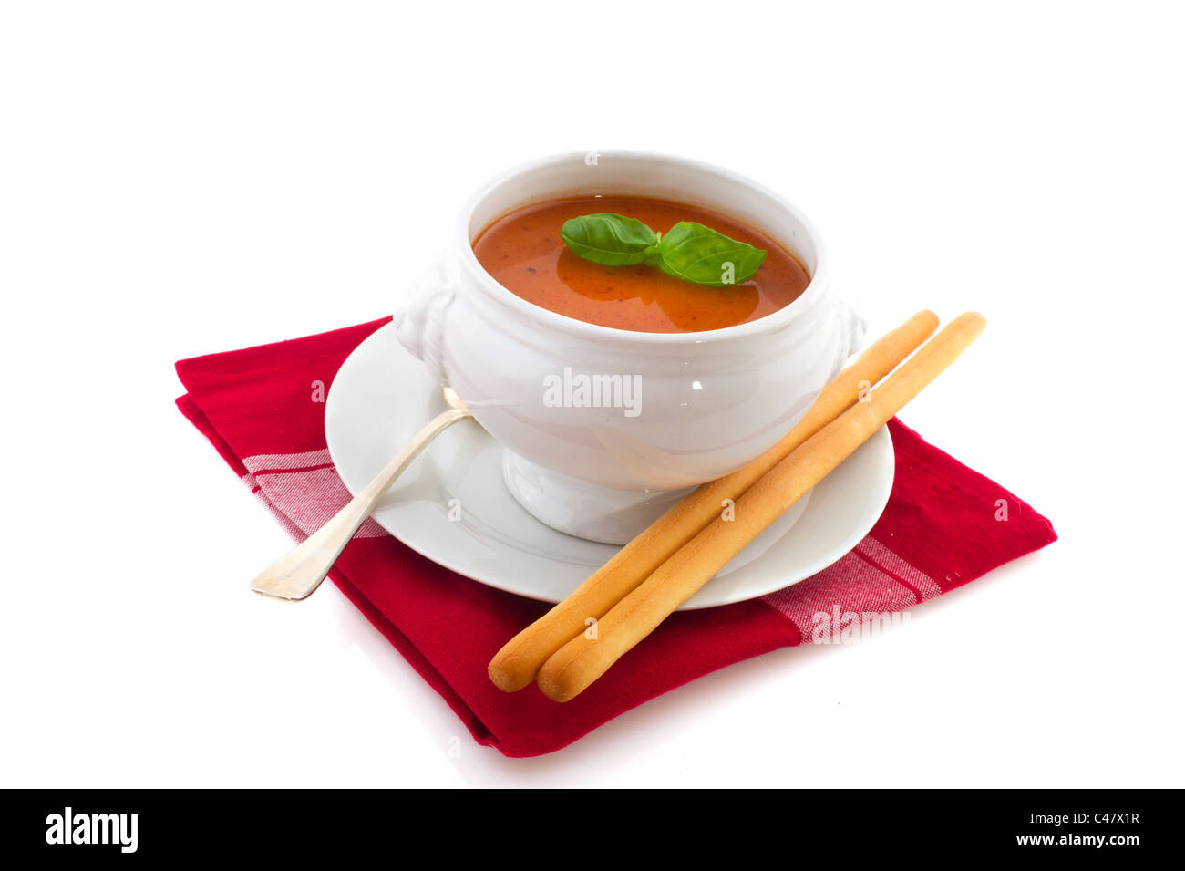 Porzione di zuppa di pomodoro in bianco ciotola di zuppa con bastoni e basilico Foto Stock