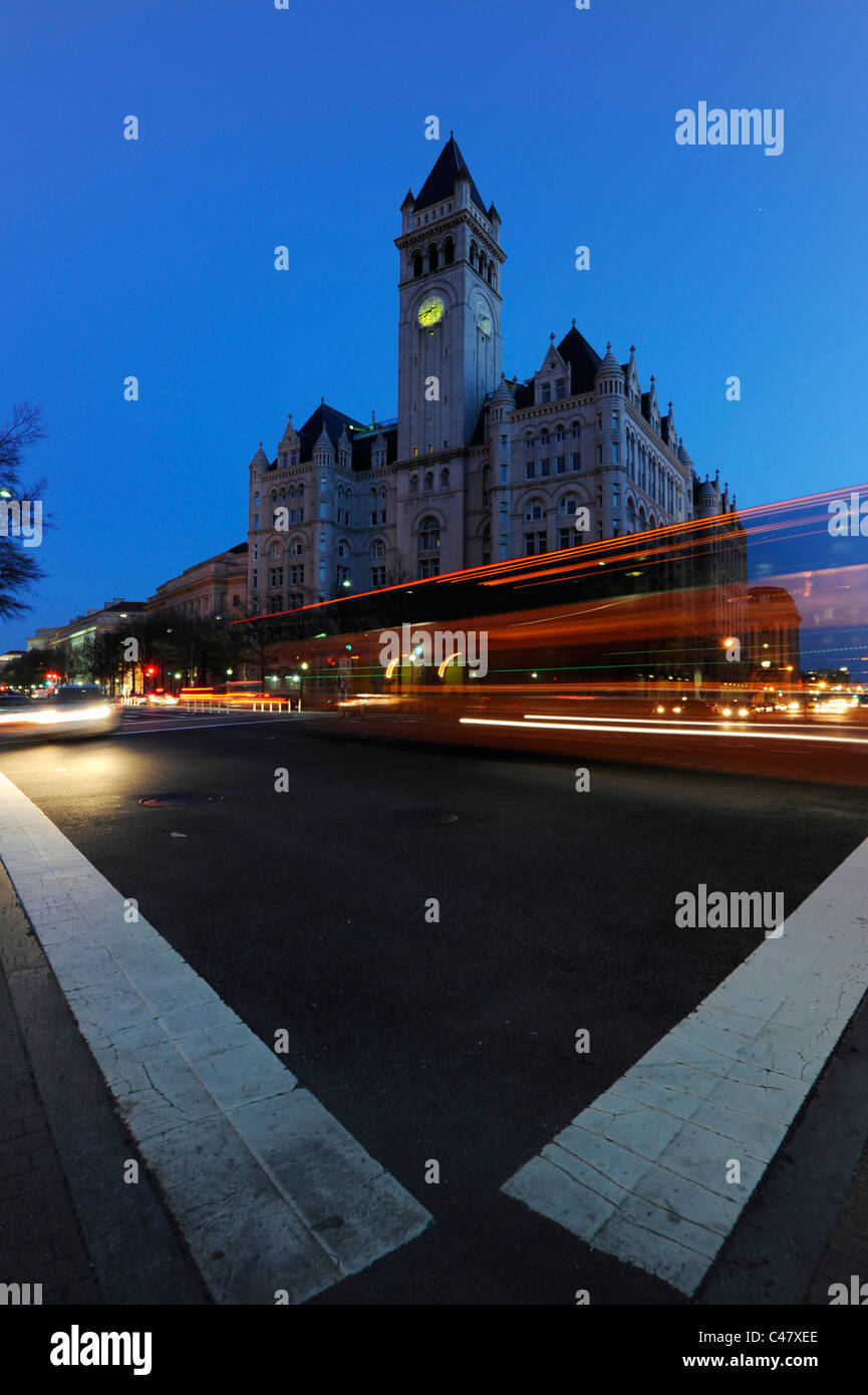 Una velocità del bus verso il basso Pennsylvania Avenue al crepuscolo di fronte al vecchio ufficio postale Pavilion di Washington DC. Foto Stock