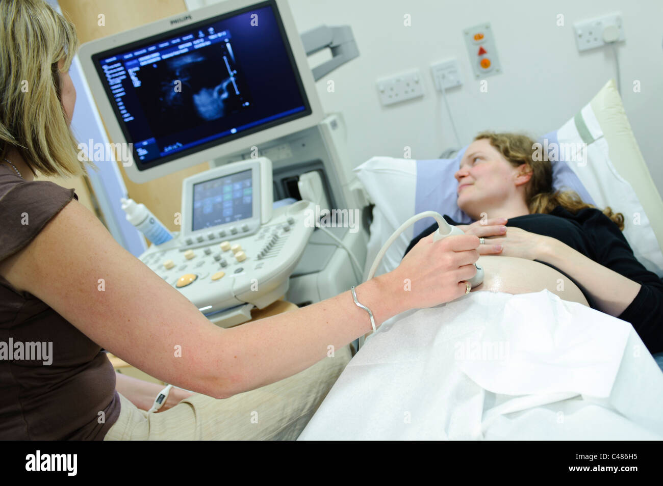 Donna incinta su paziente consultando la tabella di scansione a ultrasuoni dal medico donna Foto Stock
