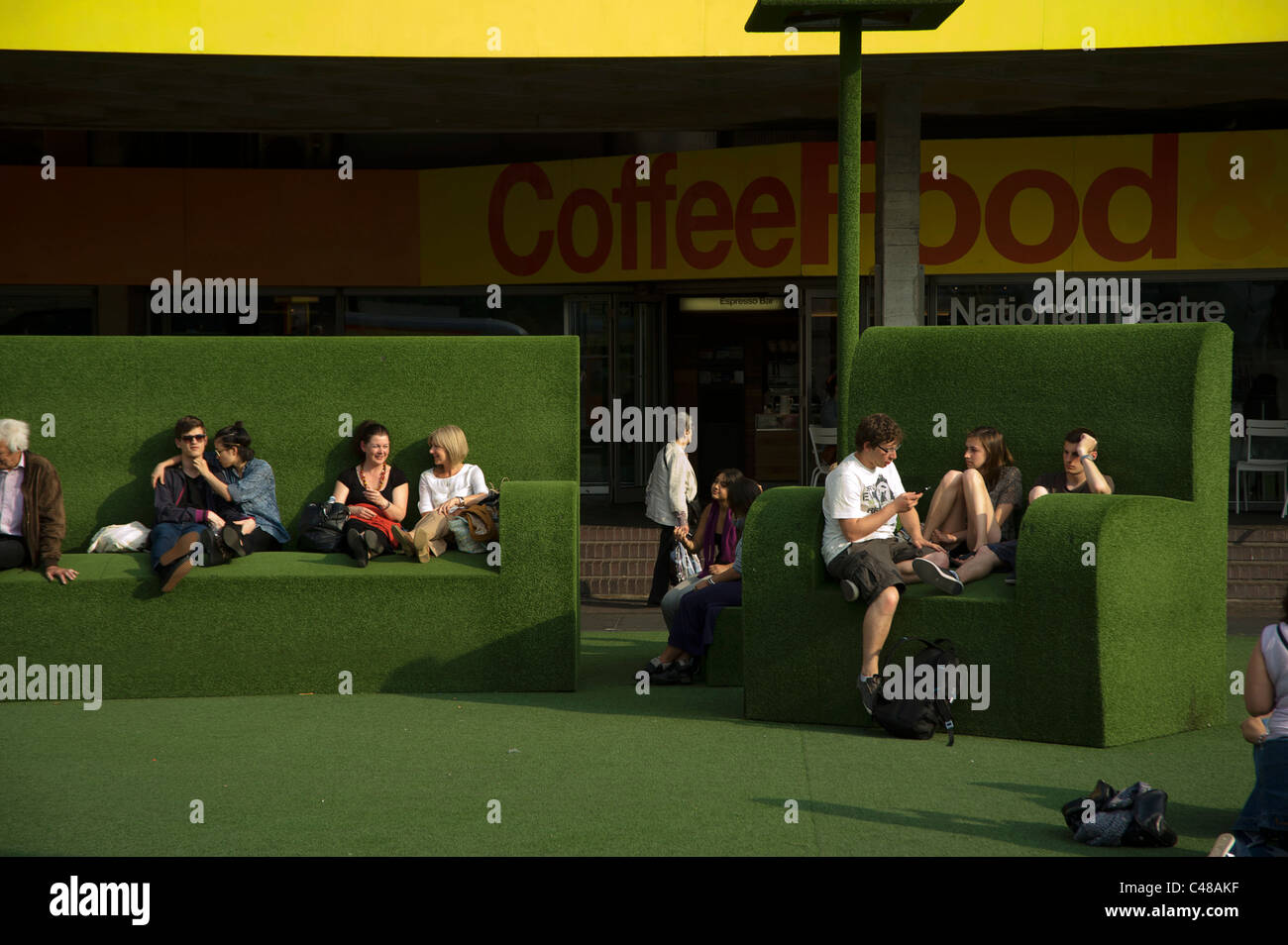Gente seduta sul verde gigante astroturf divano e poltrona Foto Stock