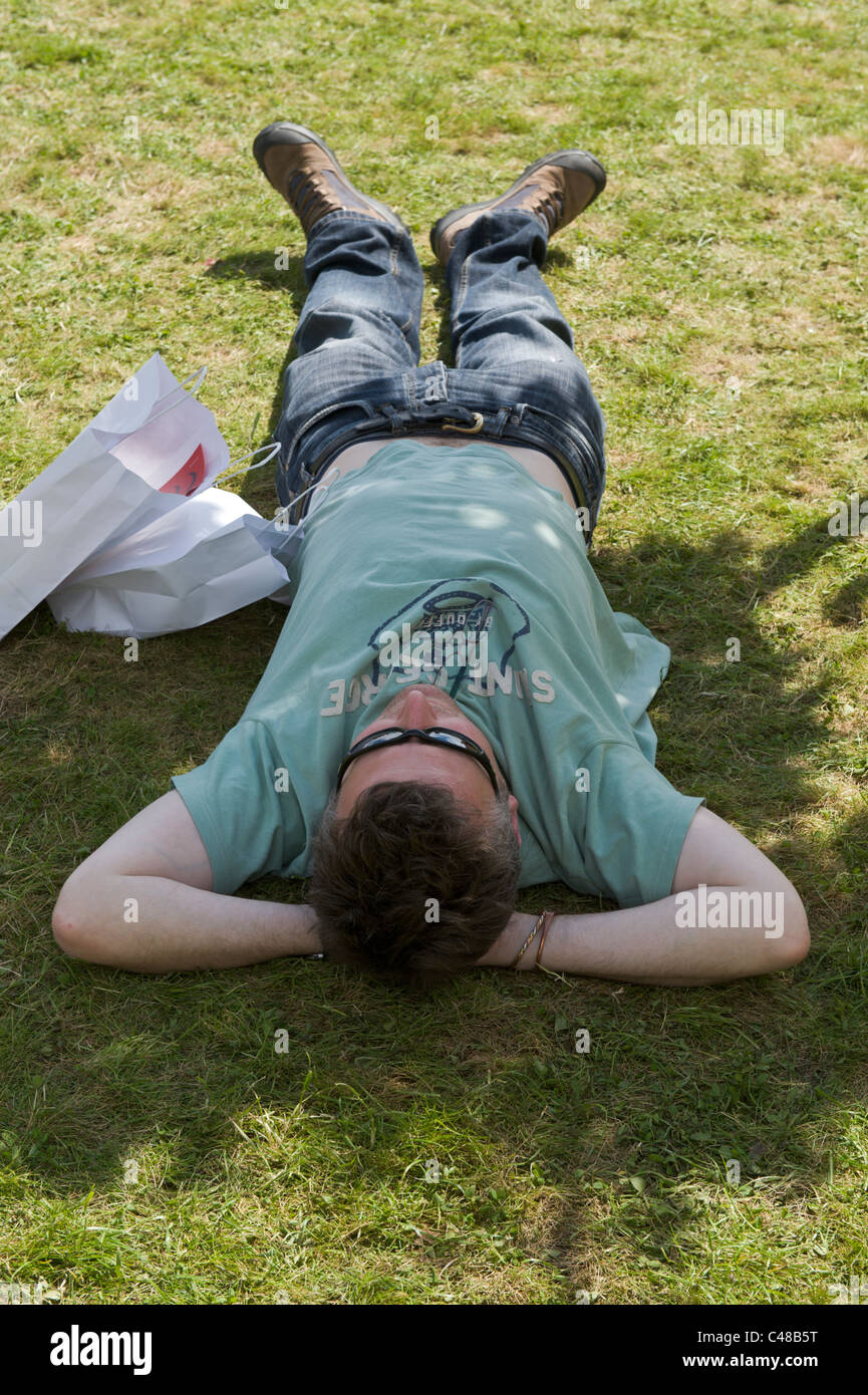 Uomo disteso sull'erba che sonnecchia in ombra di alberi a Hay Festival 2011 Foto Stock