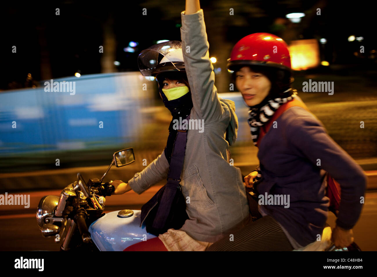 Giovani donne di guidare una moto attraverso la notte, Taipei, Taiwan, 30 ottobre 2010. Foto Stock