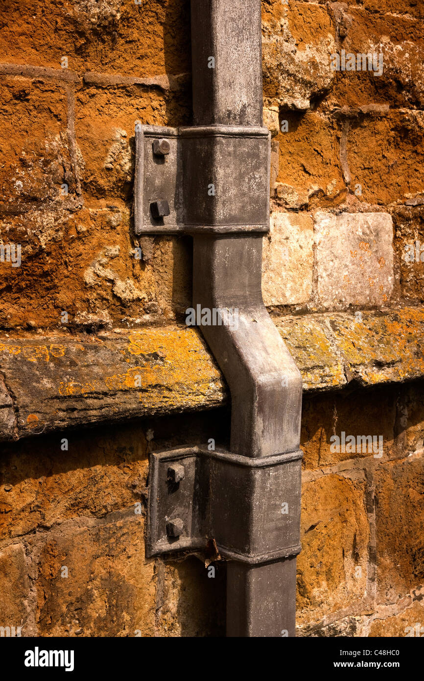 Il vecchio tubo di piombo drainpipe sul vecchio muro rustico di St Marys Chiesa, Ashby Folville, Leicestershire, England Regno Unito. Foto Stock