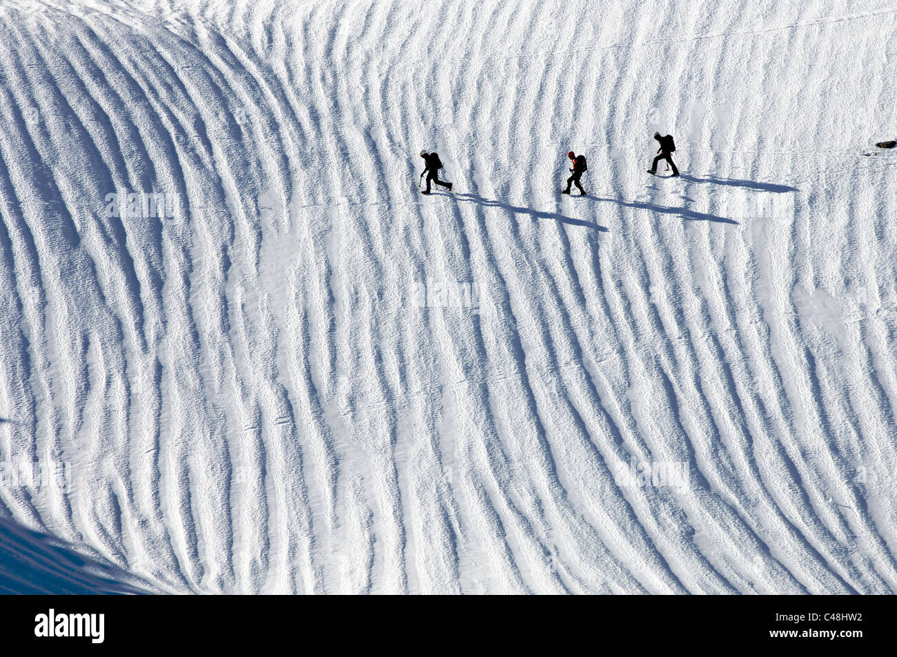 Tre gli scalatori che attraversa un snowfield nei Pirenei Foto Stock