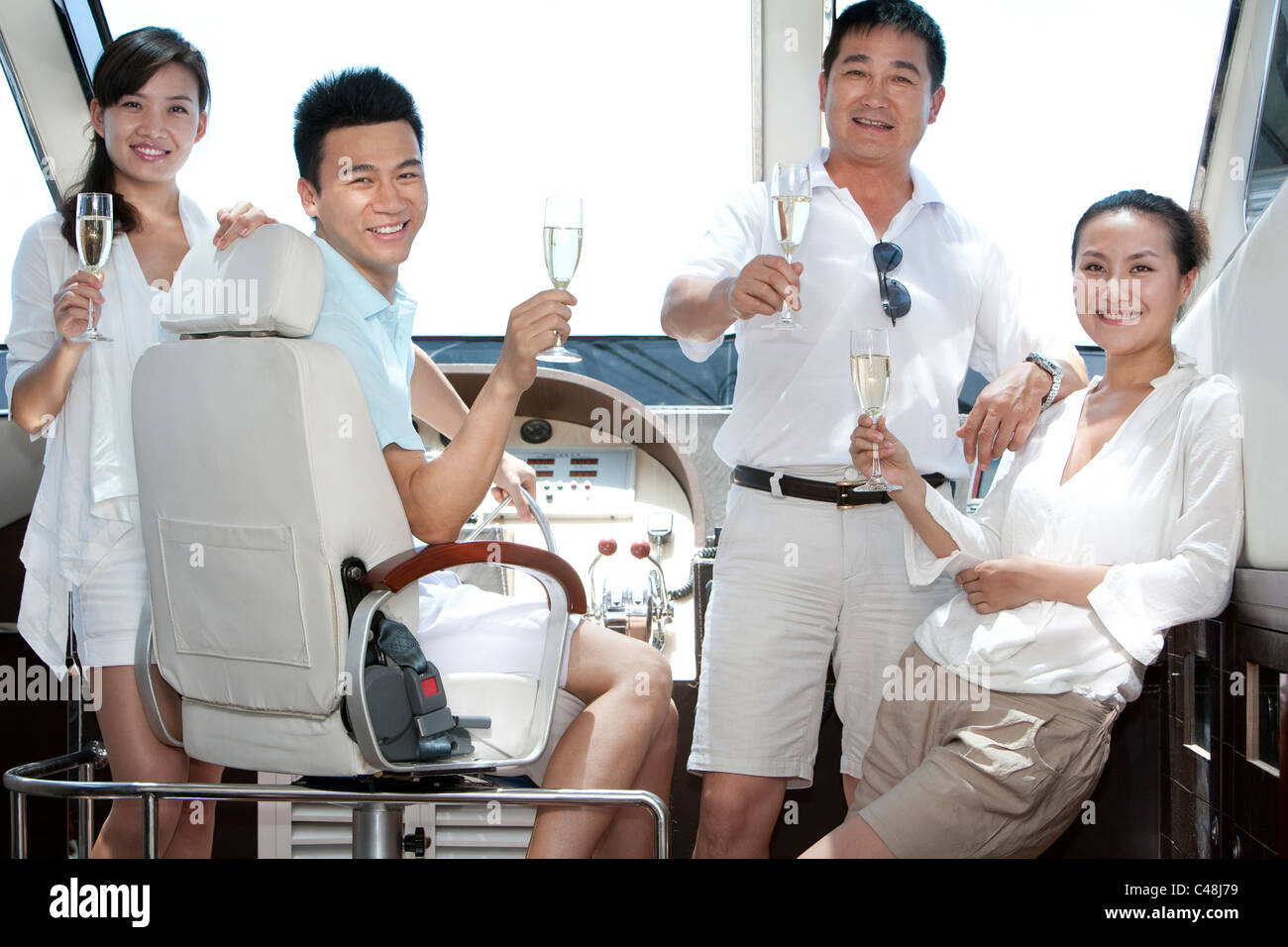 Amici di Champagne di tostatura su un yacht Foto Stock