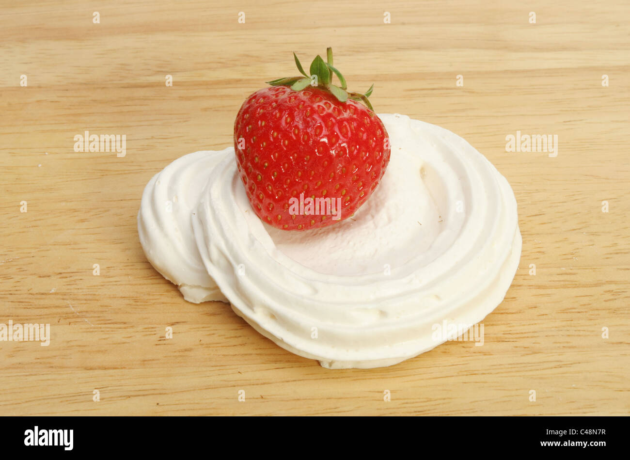 Single fragole mature in un nido di meringa su una tavola di legno preparazione alimentare board Foto Stock