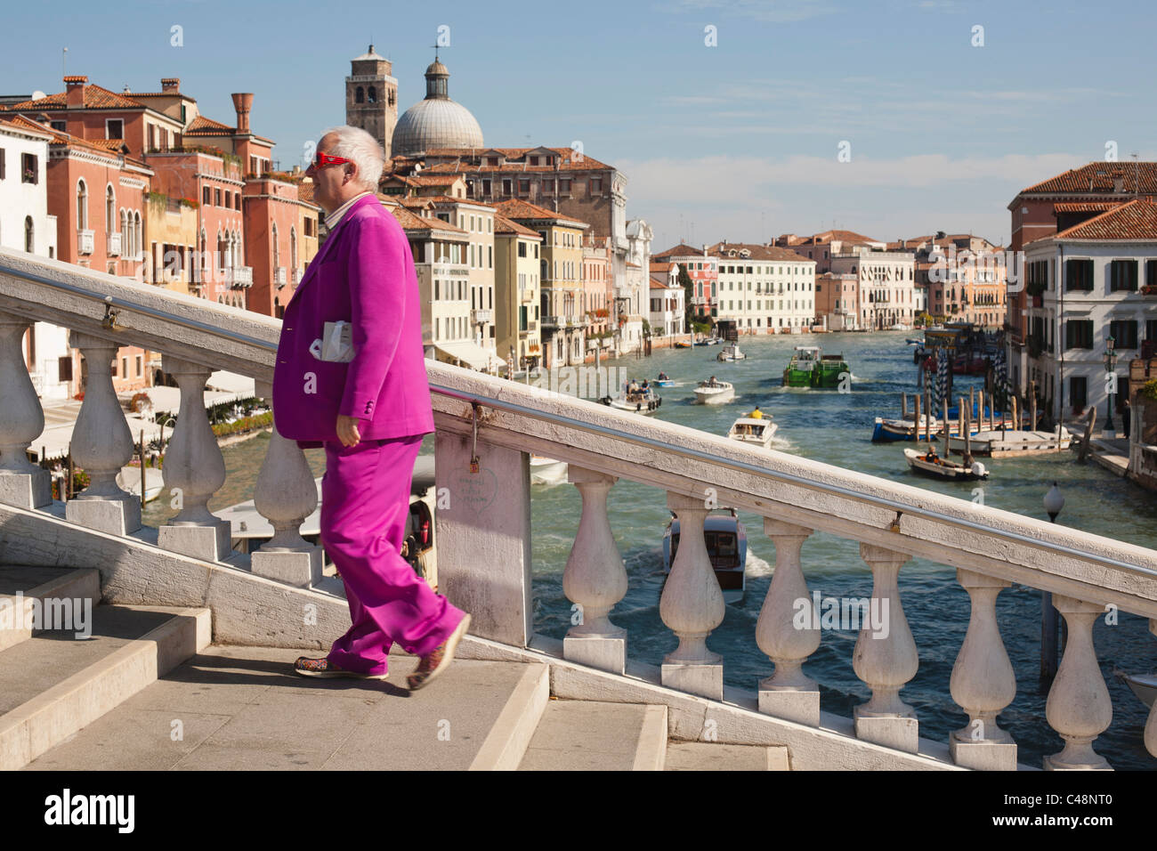 Un colorfully vestito uomo attraversando un ponte a Venezia, Italia. Foto Stock