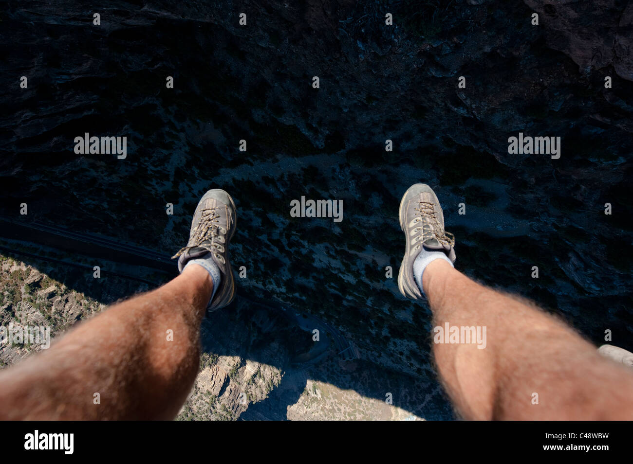 I piedi di un uomo si aggirano sulla i-70 e sul fiume Colorado nel Glenwood Canyon mentre si trova sull'altalena gigante delle Glenwood Caverns Adventure P Foto Stock