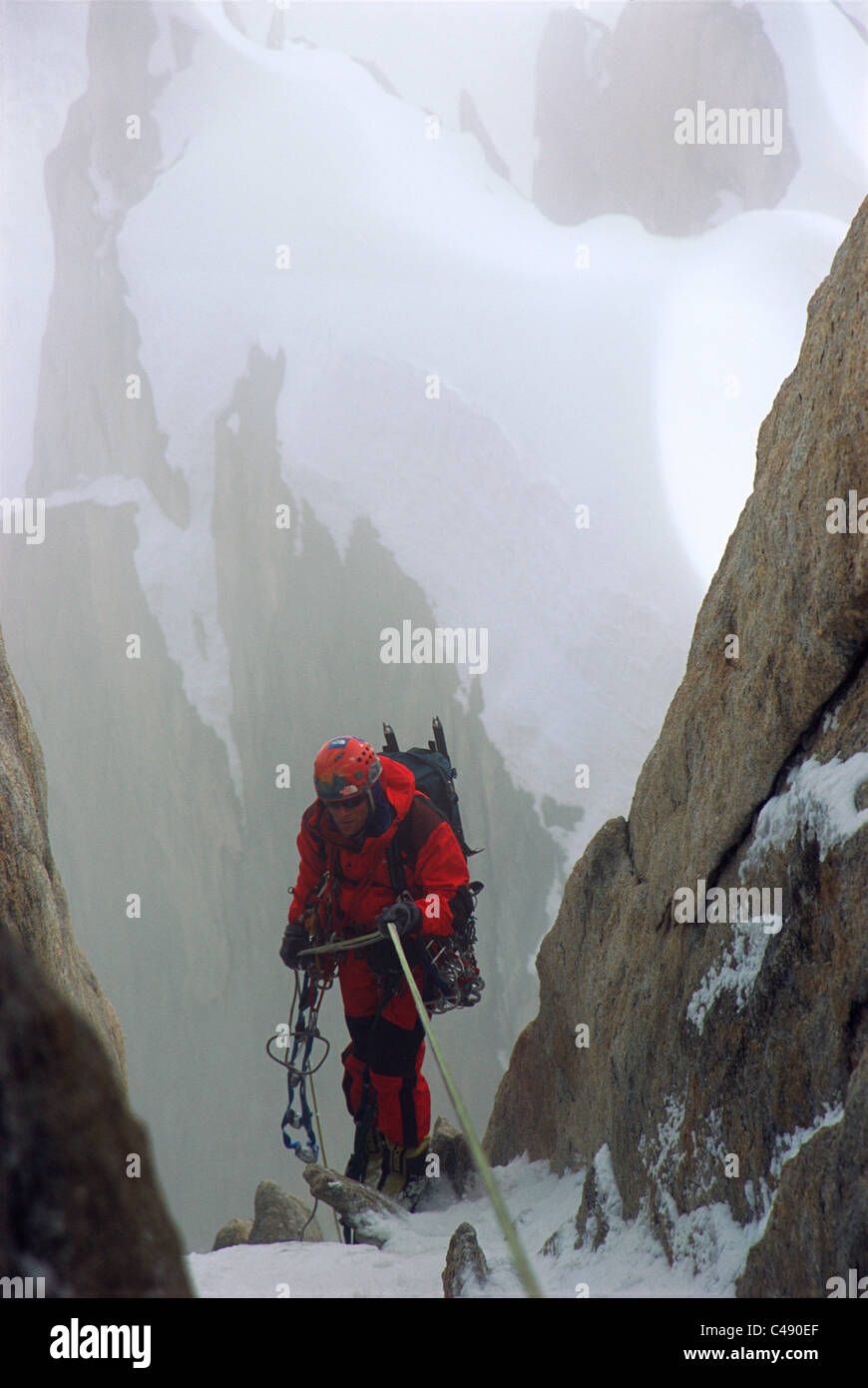 Un uomo rappels verso il basso sul lato di una montagna durante le tempeste. Il Karakoram, Pakistan. Foto Stock