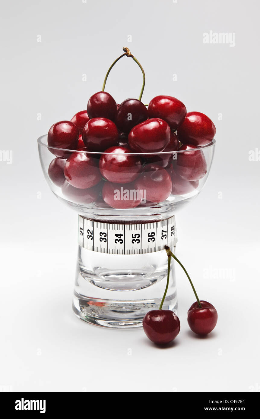 Le ciliegie di piatto di vetro con nastro di misurazione Foto Stock