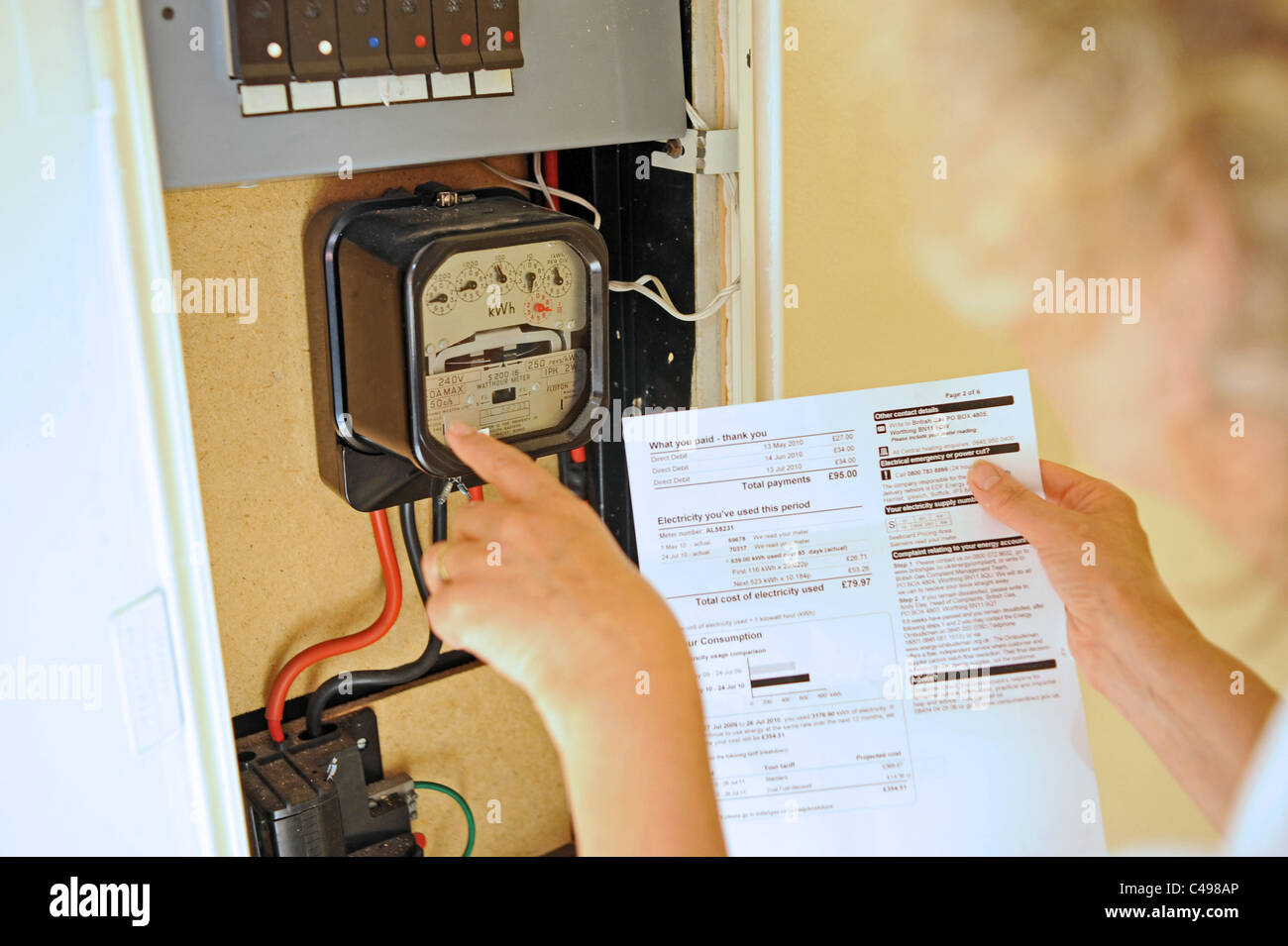 Donna contemplando l'aumento dei prezzi dell'energia e delle fatture nel Regno Unito come lei legge il suo contatore elettrico Foto Stock