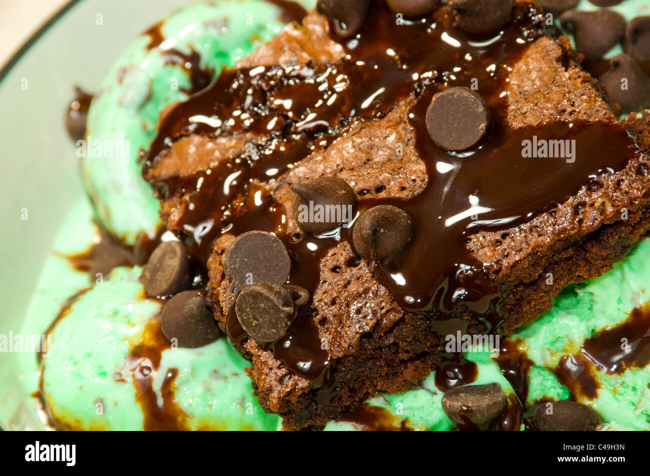 Un Brownie al cioccolato guarnita con pezzetti di cioccolato e sciroppo sulla cima di menta Gelato al cioccolato. Foto Stock
