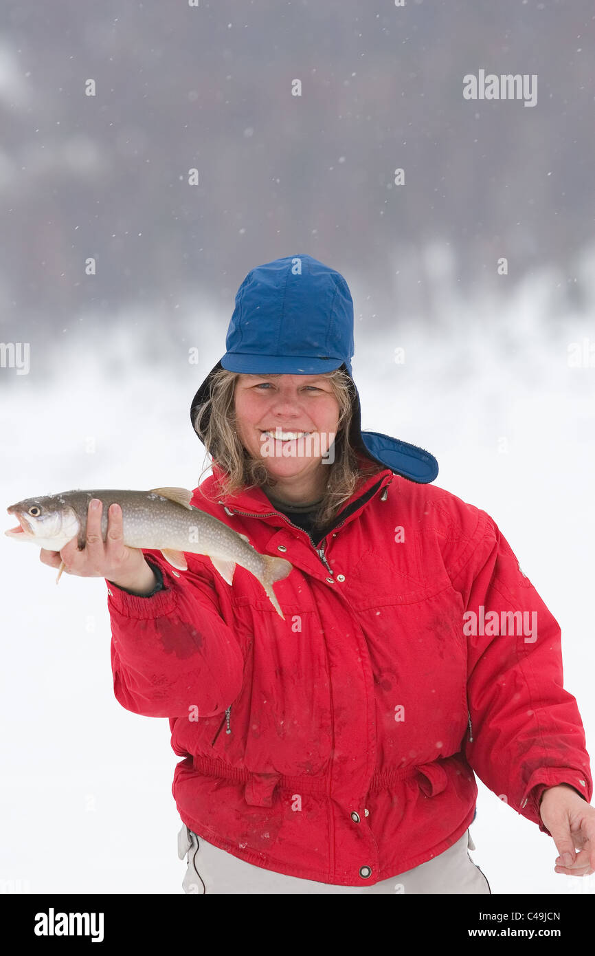 Una donna la pesca sul ghiaccio in possesso di una trota di lago Foto Stock