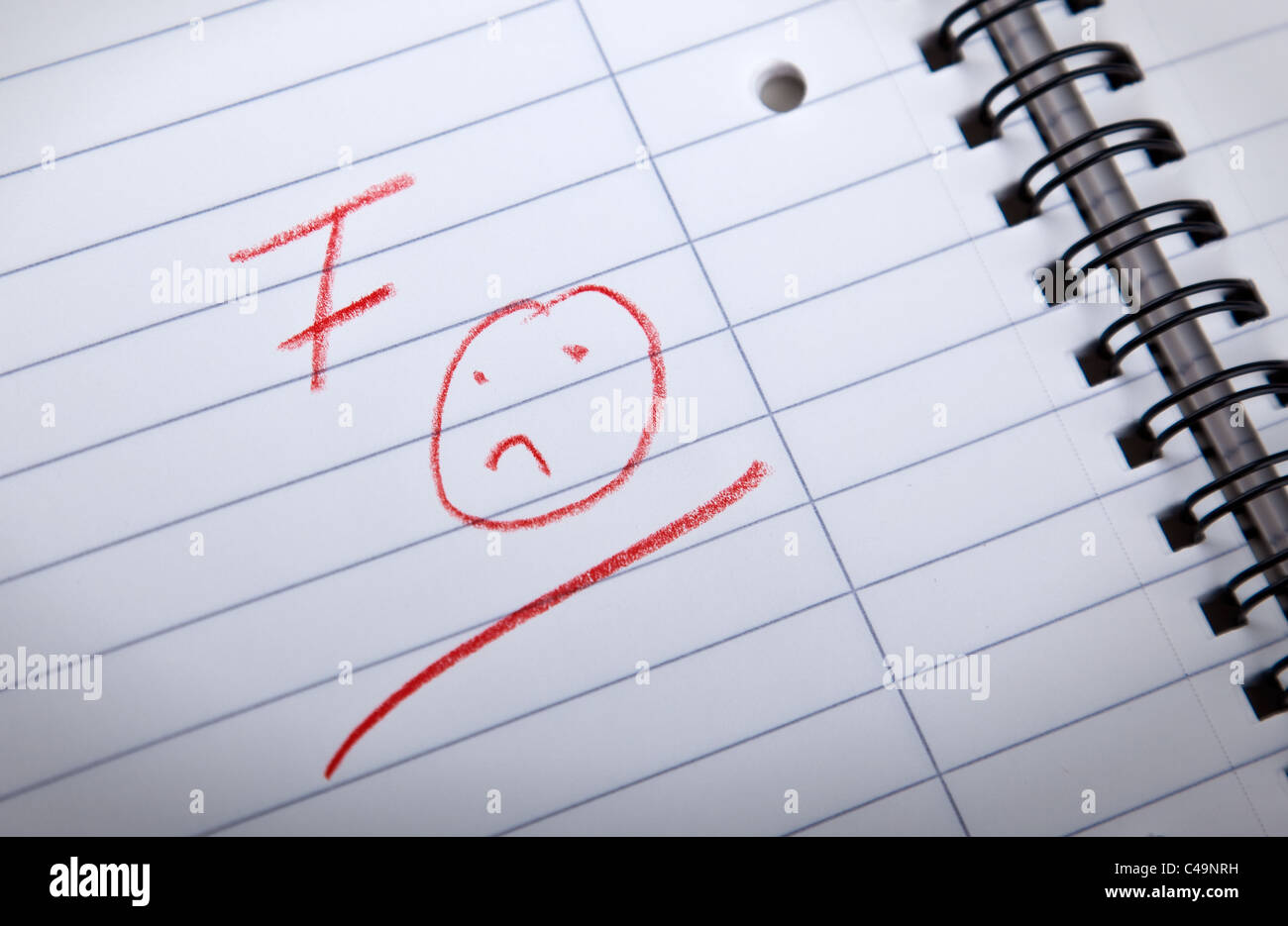 F grado e un triste sorridenti, scritto in lettere rosse in una spirale pad, shallow DOF Foto Stock