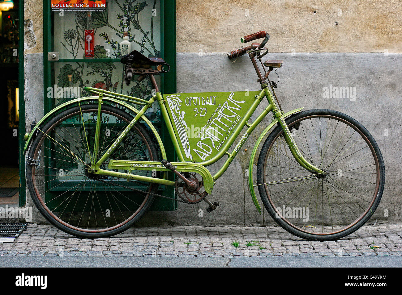 Un verde vecchia bicicletta come un segno pubblicità appoggiata contro una  vetrina vicino all'entrata di un negozio di assenzio a Praga Foto stock -  Alamy