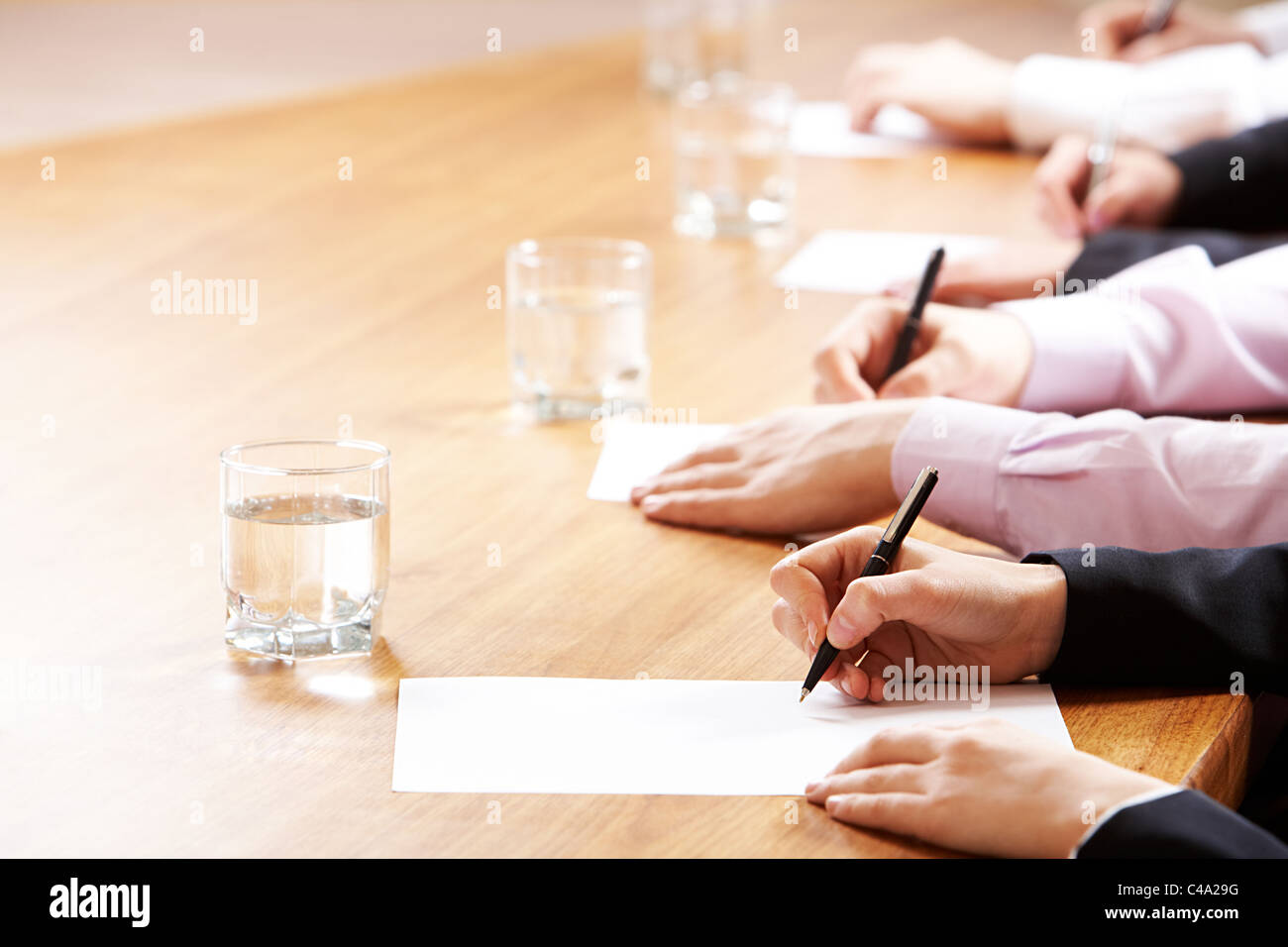 Mani tenendo le penne e scrivere qualcosa durante la lezione o seminario aziendale Foto Stock