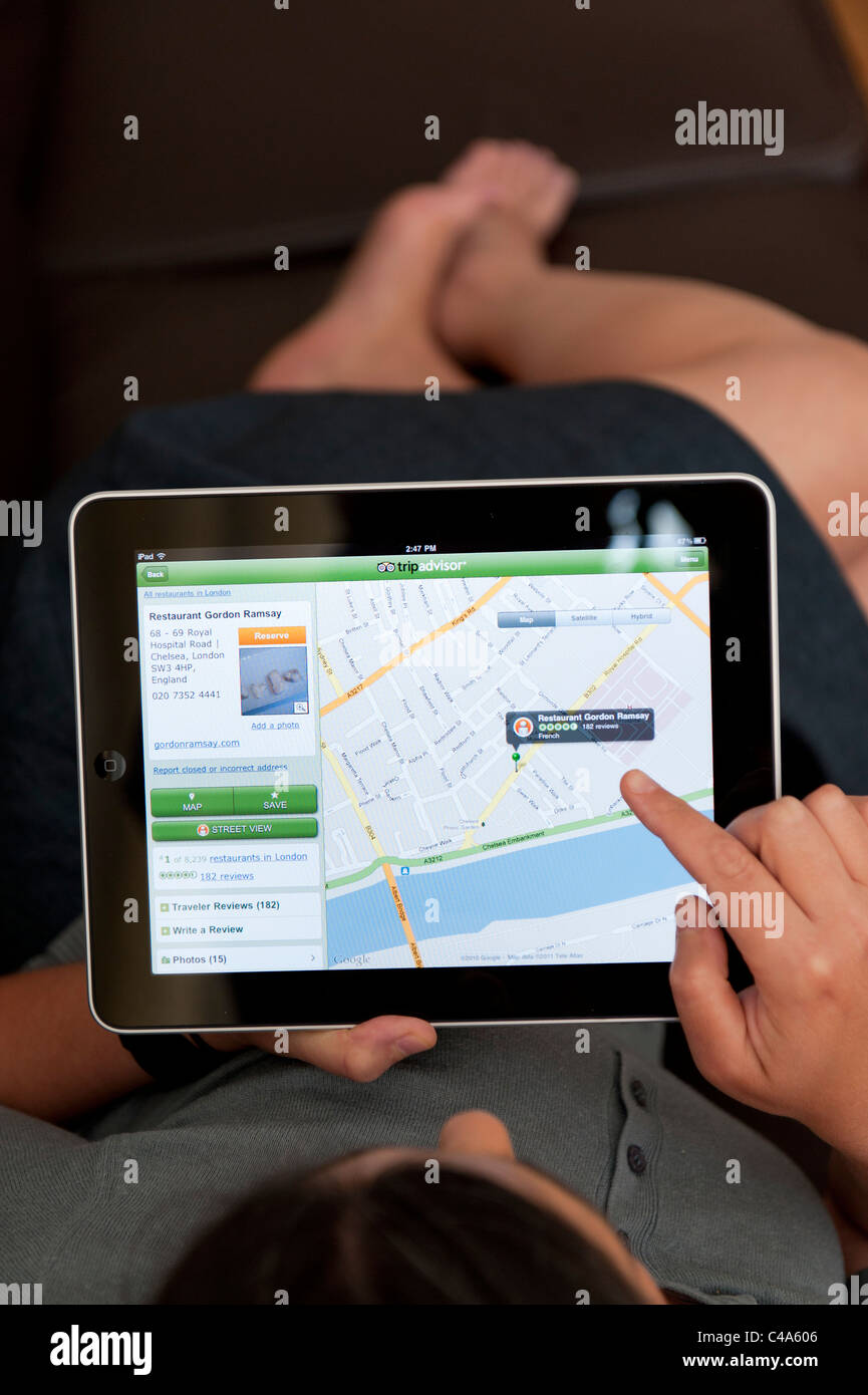 Close up della donna che utilizza iPad tavoletta digitale computer per leggere Recensione ristorante a Londra usando app di Tripadvisor Foto Stock
