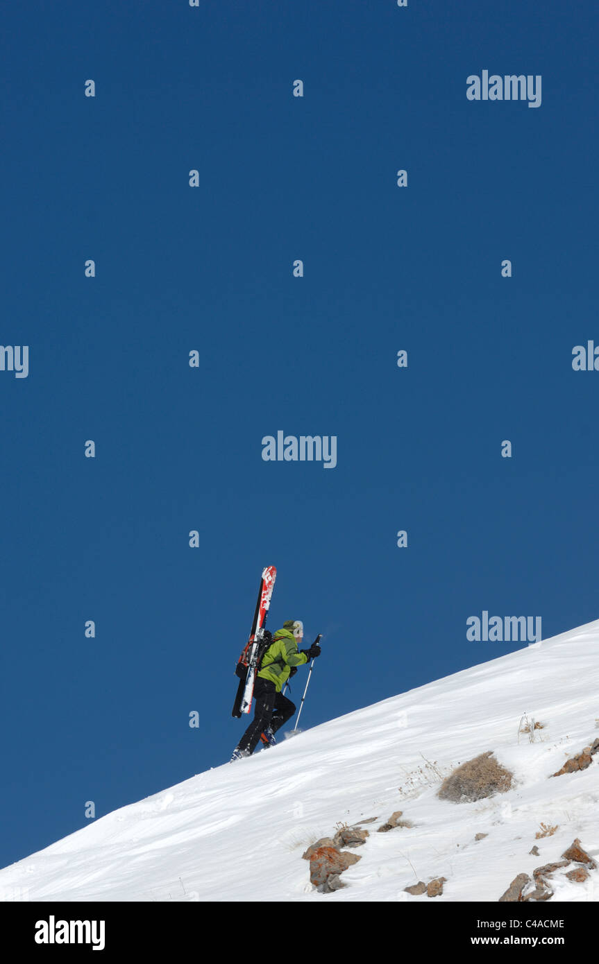 Tre backcountry sci alpinisti portare sci su una coperta di neve linea di cresta contro un profondo cielo blu in Dizin Iran Foto Stock